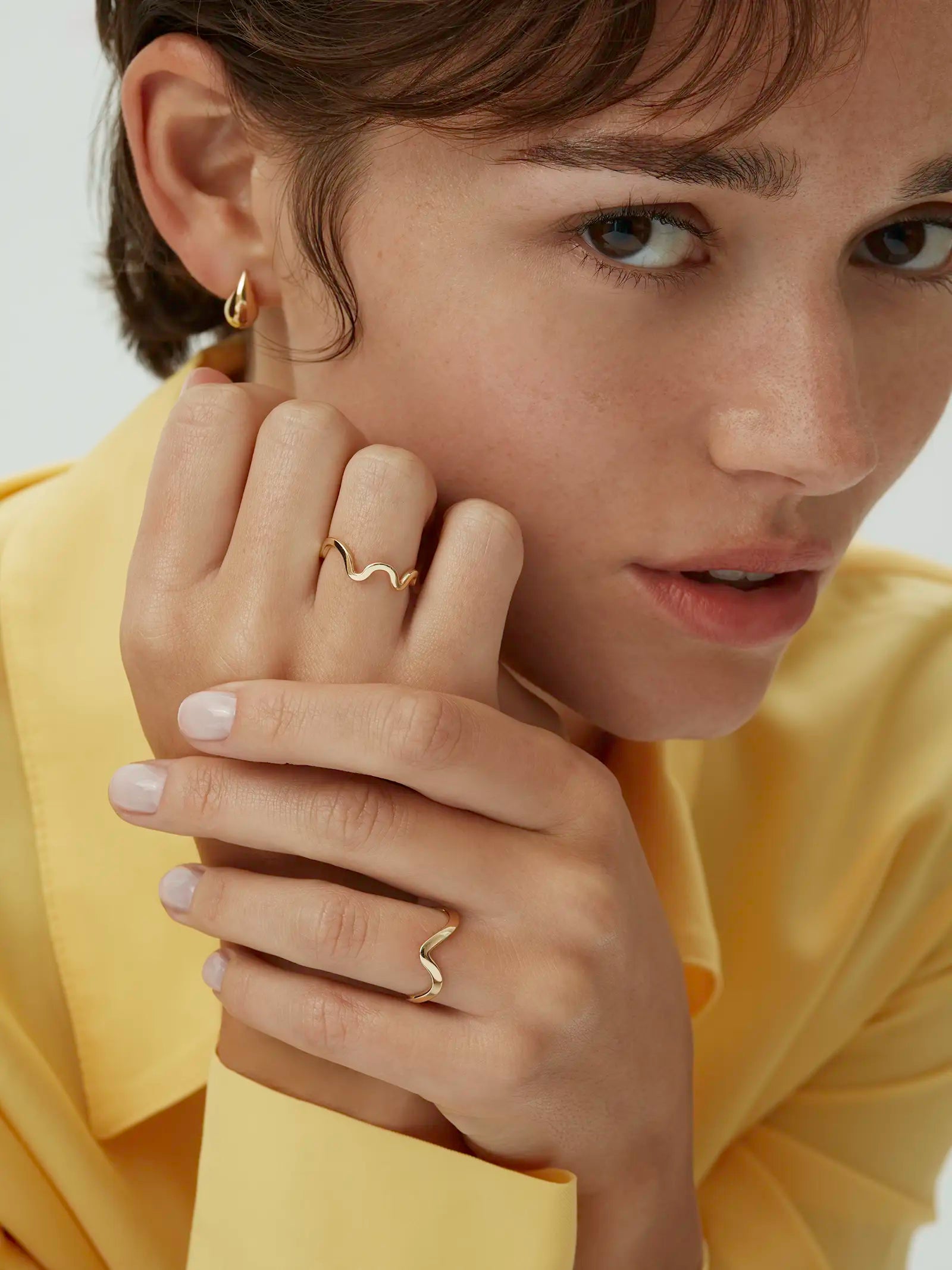 Model wearing two wavy band rings including the yellow gold Kyma Rhythm ring - Enea Studio