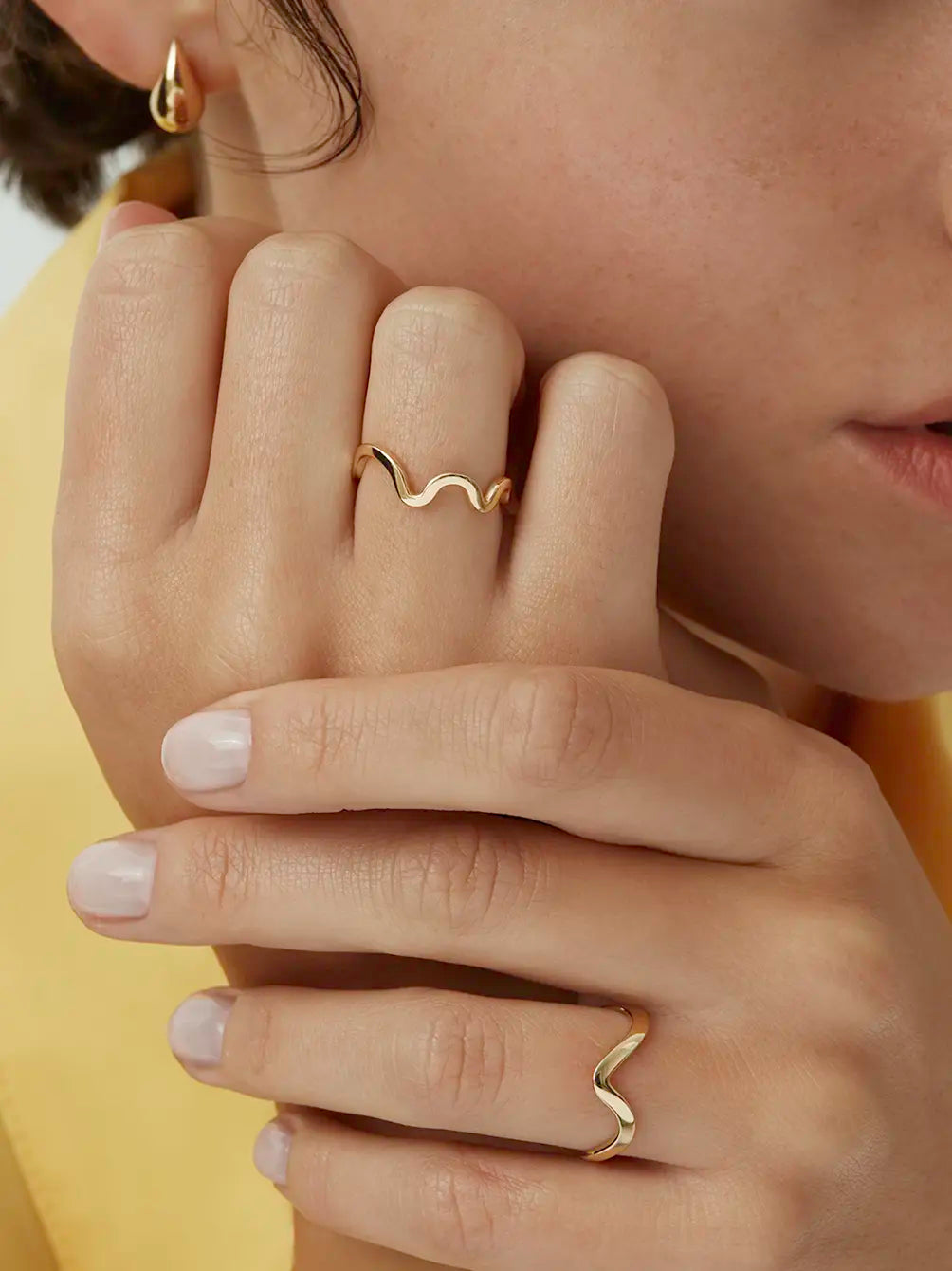 Close up of a model wearing the yellow gold Kyma Rhythm band ring styled with another wavy band - Enea Studio