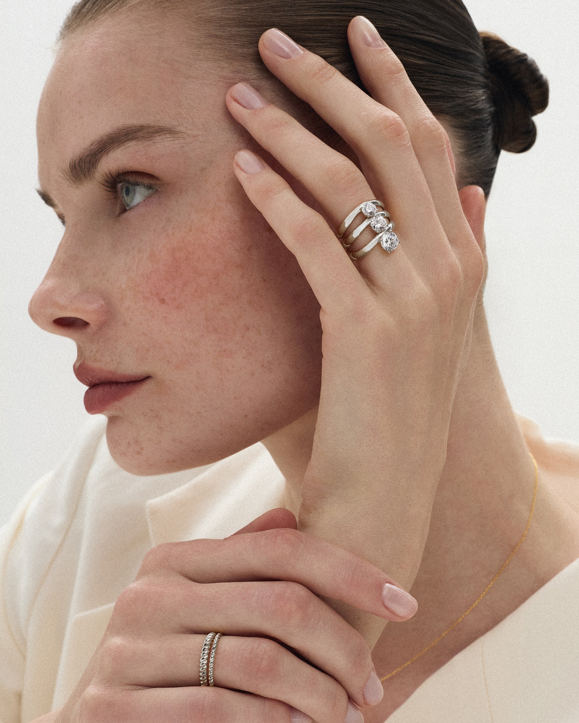 side view of a woman touching her face with her hand wearing the kyma solitaire rings in solid white gold in 0.50ct, 0.75ct and 1ct sizes on a white background