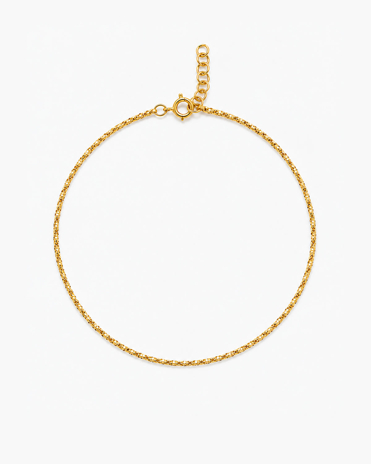 Lumière Sparkle Chain Bracelet in 14k yellow gold, a diamond cut chain with faceted links, spring ring clasp and extender, on an off-white surface. ENEA Studio