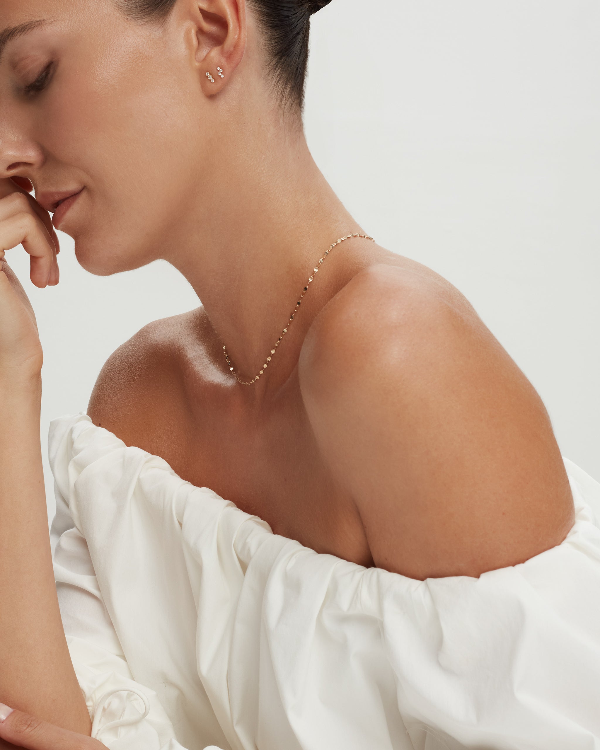 Marina mirror chain catching the light on a bare shoulder, ENEA Studio