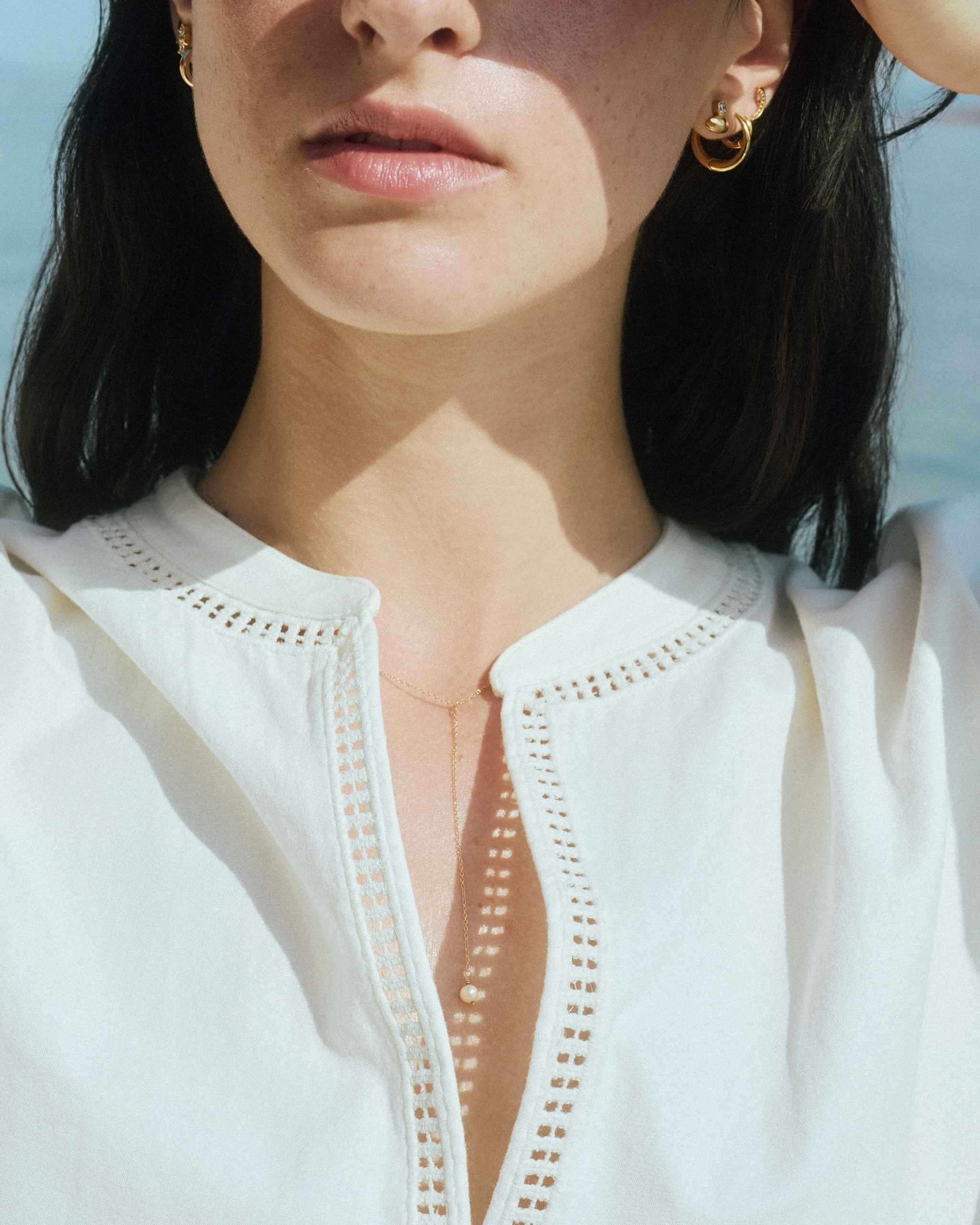 14k yellow gold lariat pearl necklace on model with white shirt showing freshwater pearl drop pendant on gold chain necklace