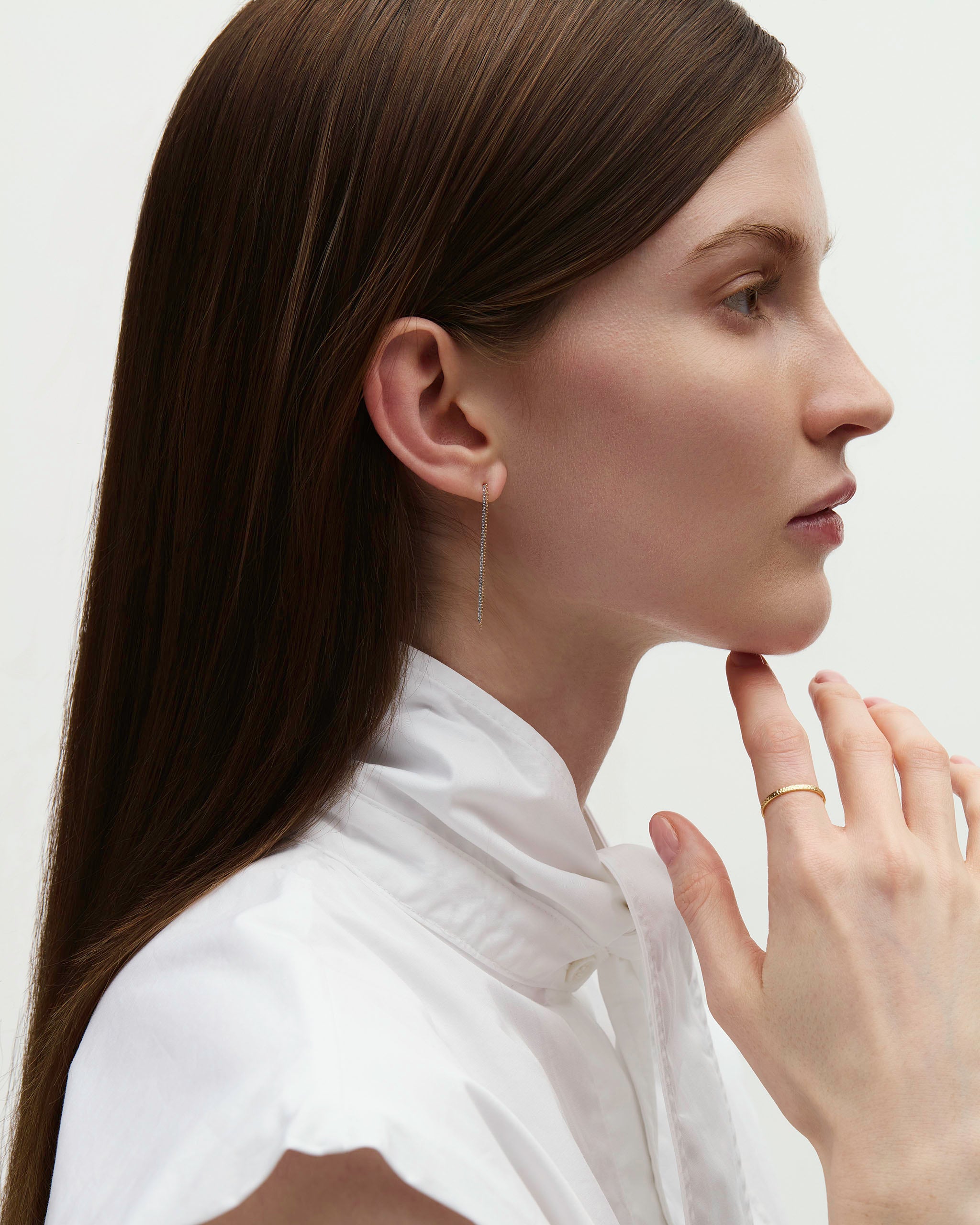 Profile portrait of model wearing Dyo Drop Chain Earrings, chain drop visible against the jaw.