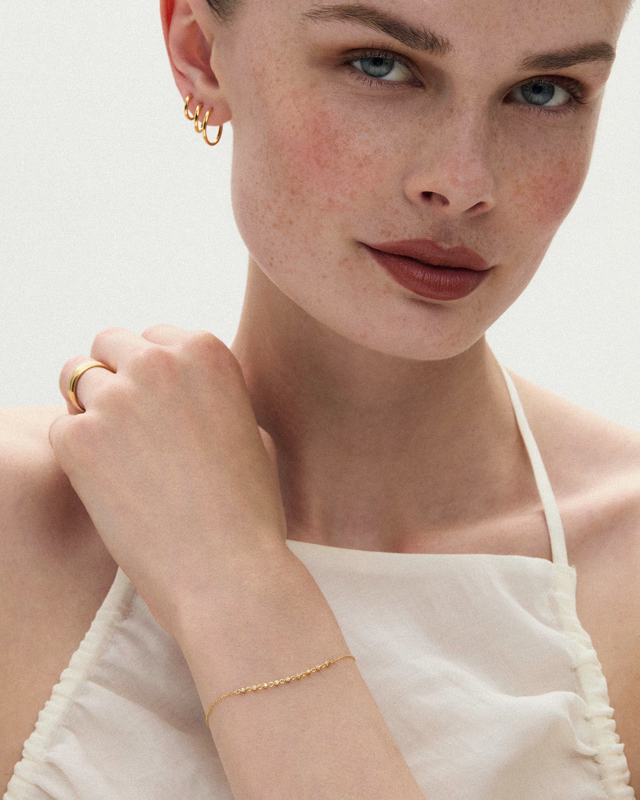 Petite tennis bracelet 14k yellow gold styled with a gold ring and three small hoop earrings