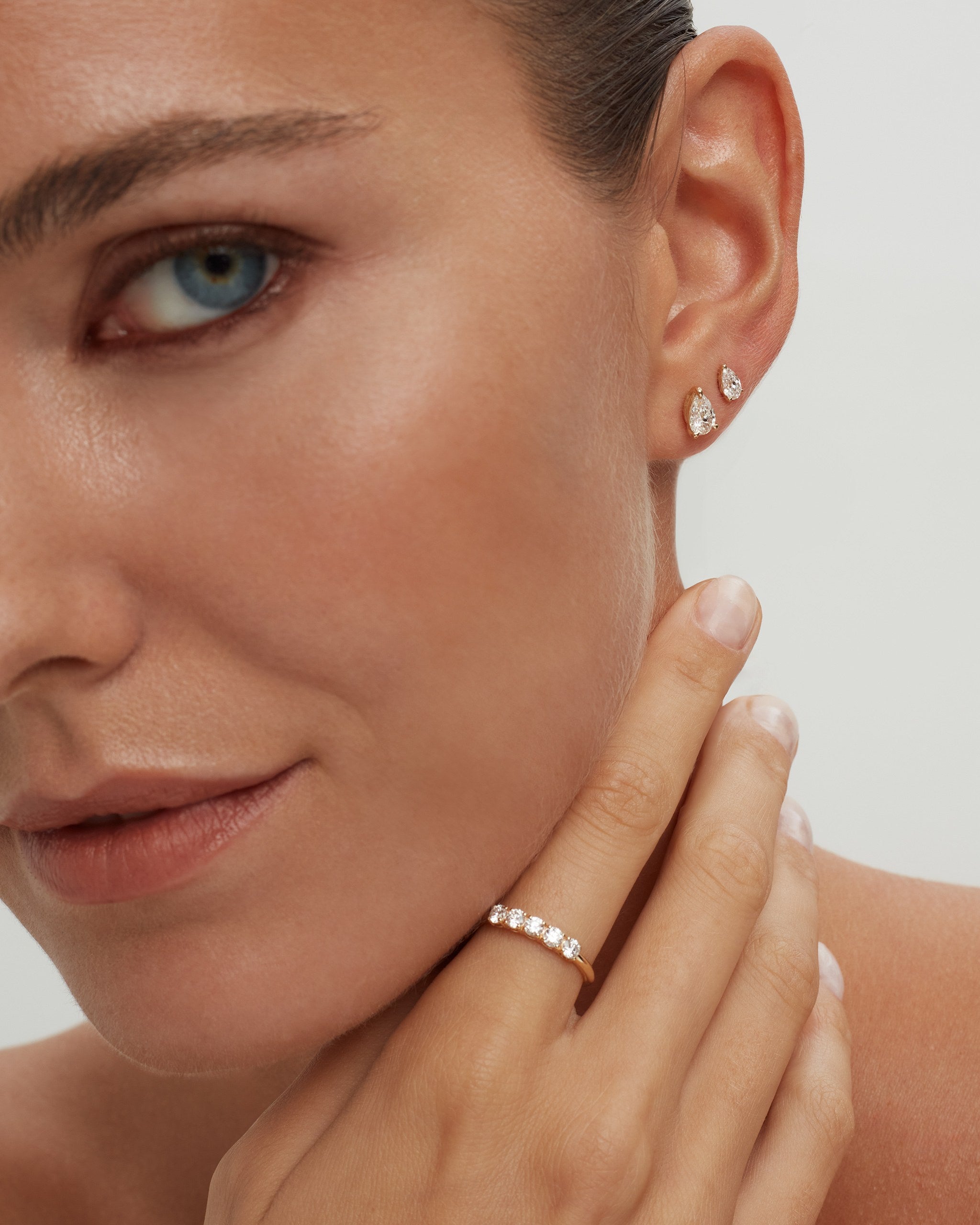 Pear lab diamond studs in 14k yellow gold worn point up with a diamond ring, ENEA Studio