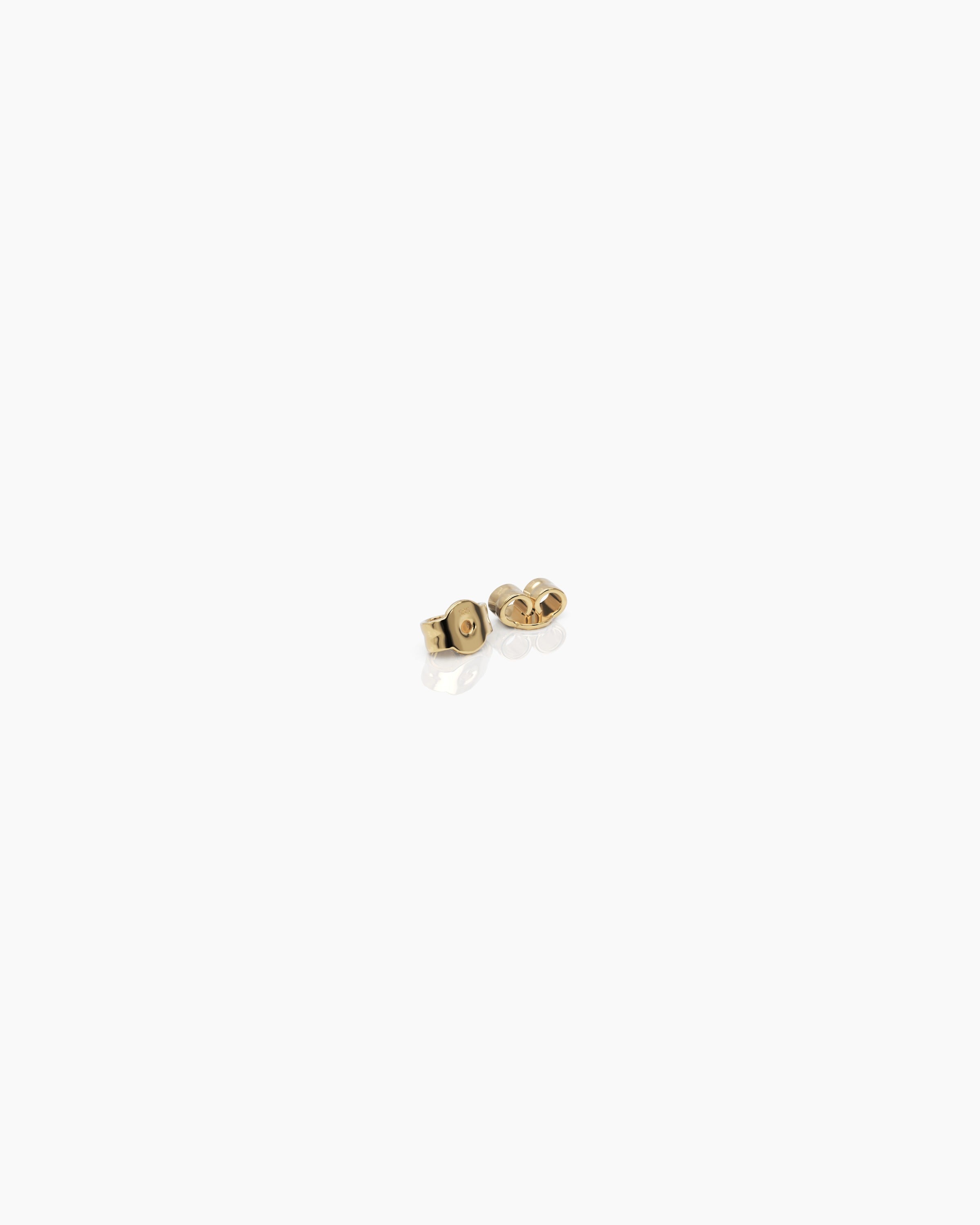 14k yellow gold push back earring closures for diamond stud earrings on an off-white surface