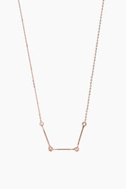 Front-facing product image of the Iris Necklace in 14k rose gold, featuring three polished bars connected with rounded loops.