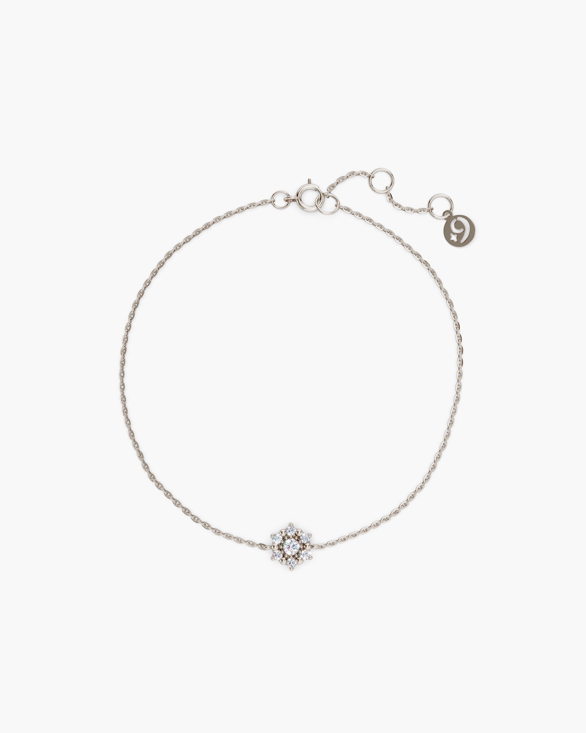Selas Diamond Cluster Bracelet in 14k white gold, top view, a seven stone lab grown diamond cluster on a fine cable chain with an adjustable extender and ENEA tag, on an off-white surface. ENEA Studio