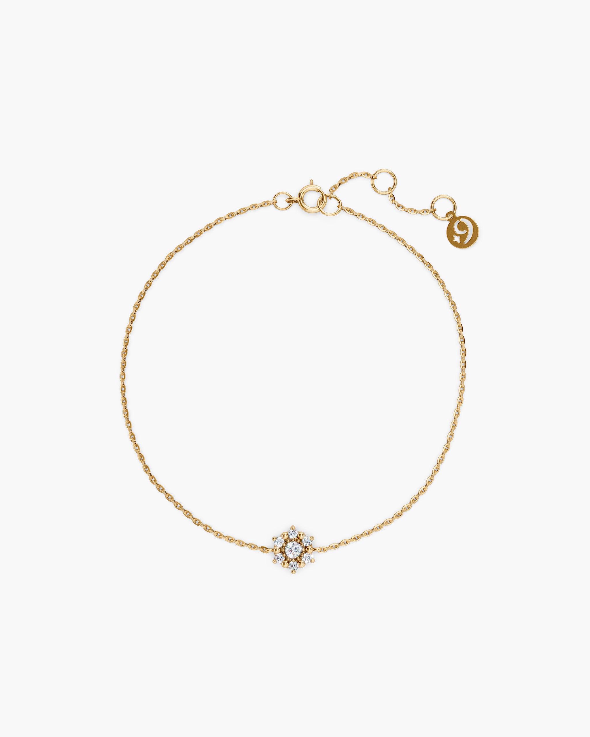 Selas Diamond Cluster Bracelet in 14k yellow gold, top view, a seven stone lab grown diamond cluster on a fine cable chain with an adjustable extender and ENEA tag, on an off-white surface. ENEA Studio