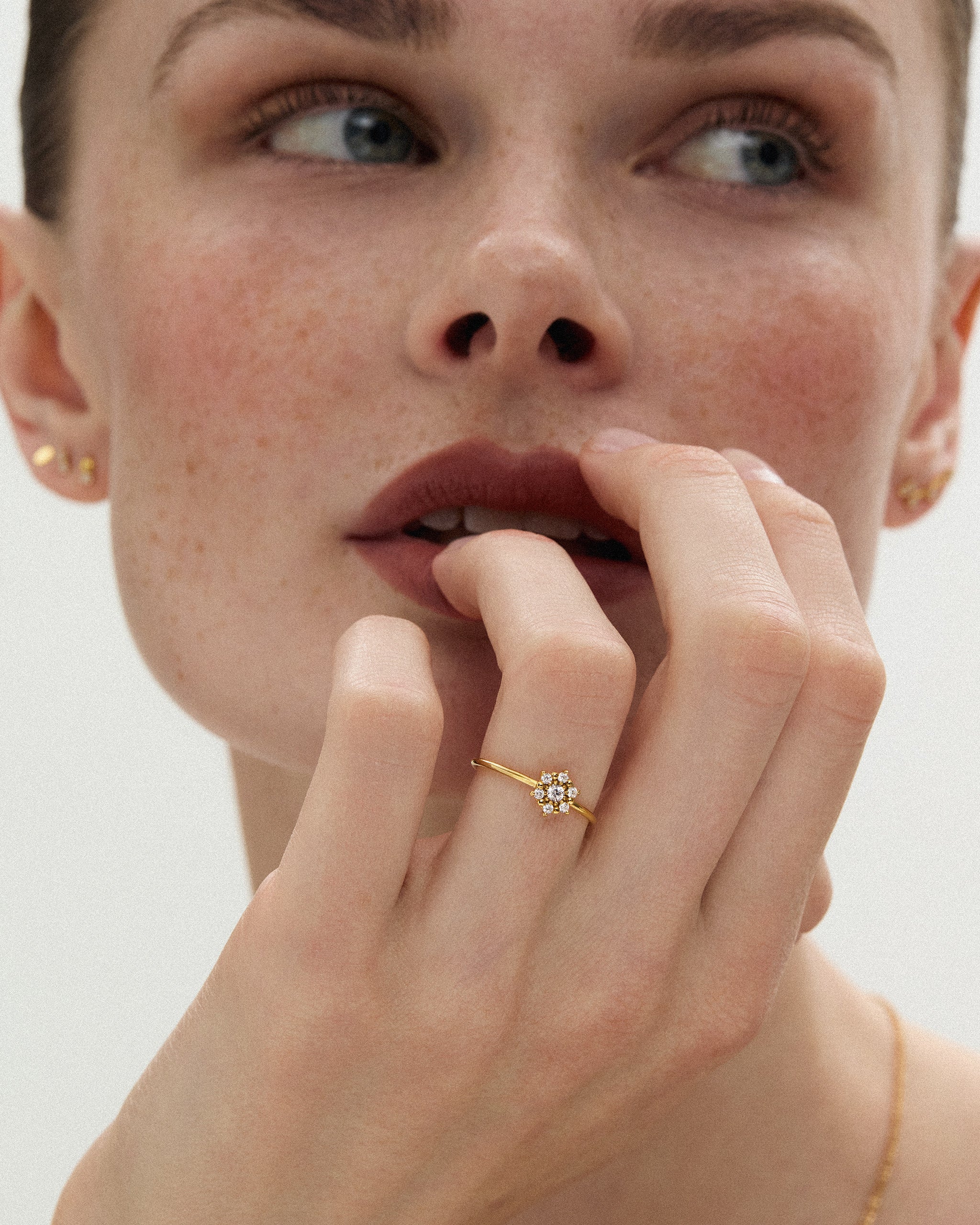 Woman wearing the Selas Diamond Cluster Ring in 14k yellow gold on her ring finger, hand raised to her lips, showing the 7.3mm cluster at true scale. ENEA Studio