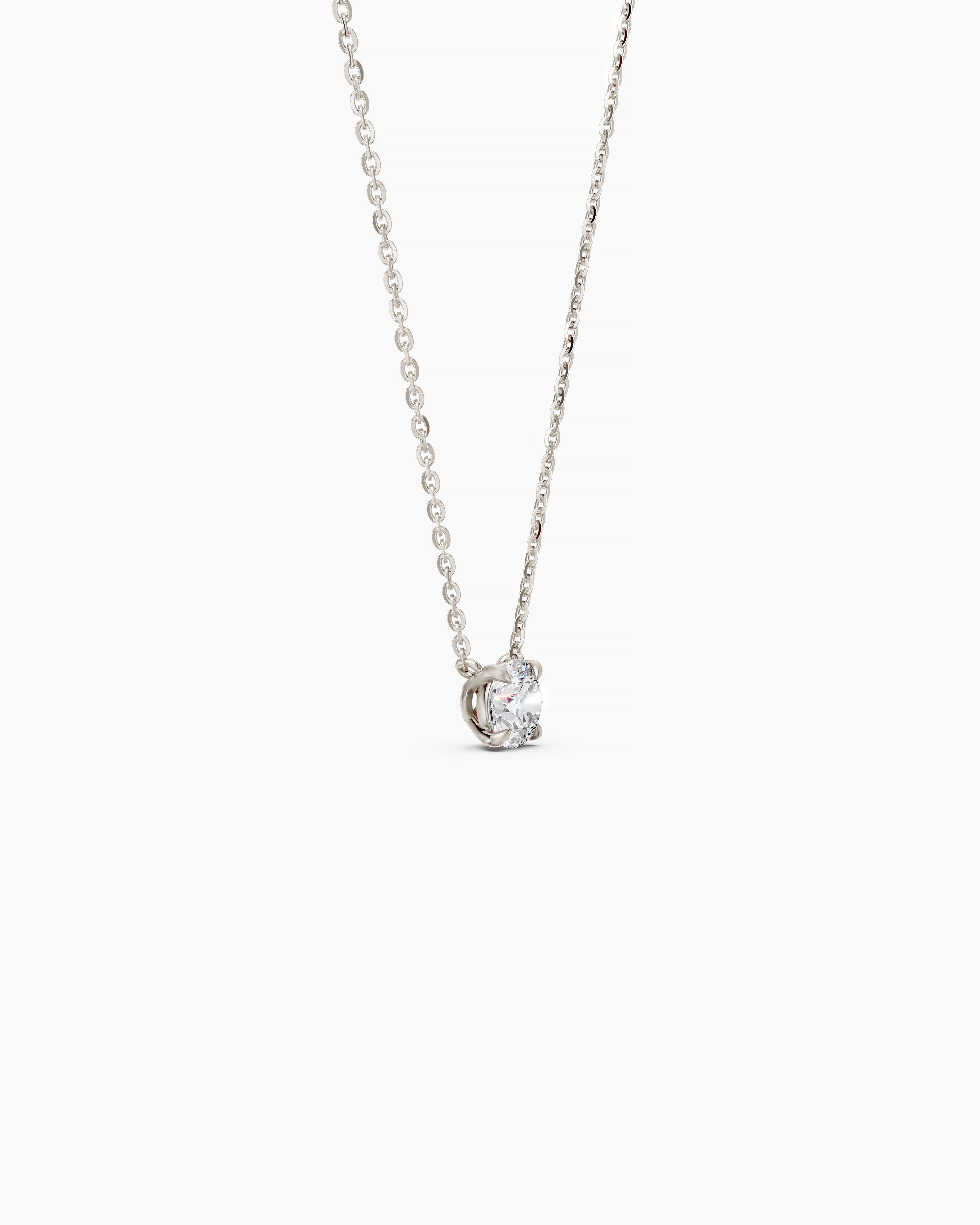 Side view of a white gold necklace with a round diamond pendant on a soft beige background