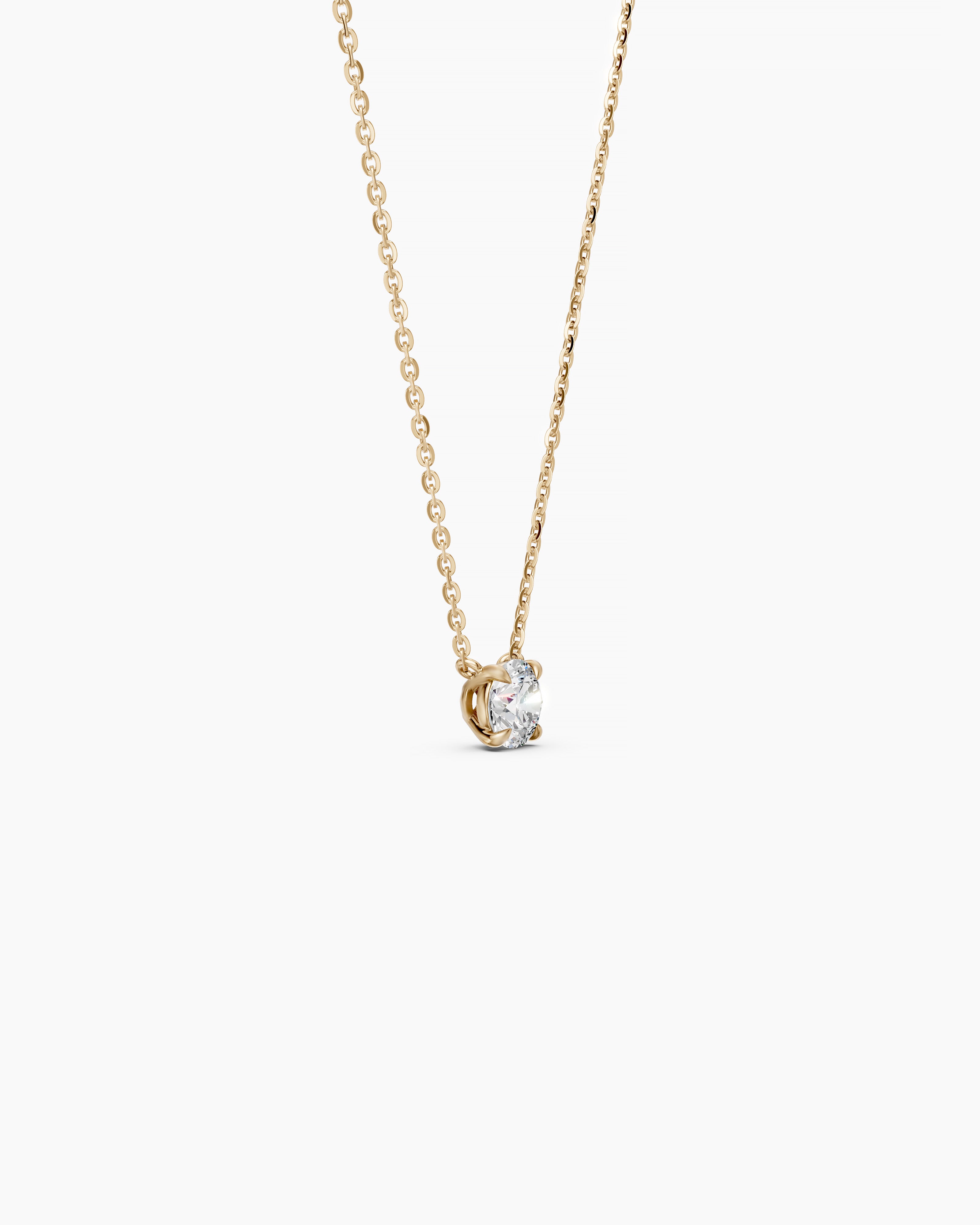 Side view of a yellow gold necklace with a round diamond pendant on a soft beige background