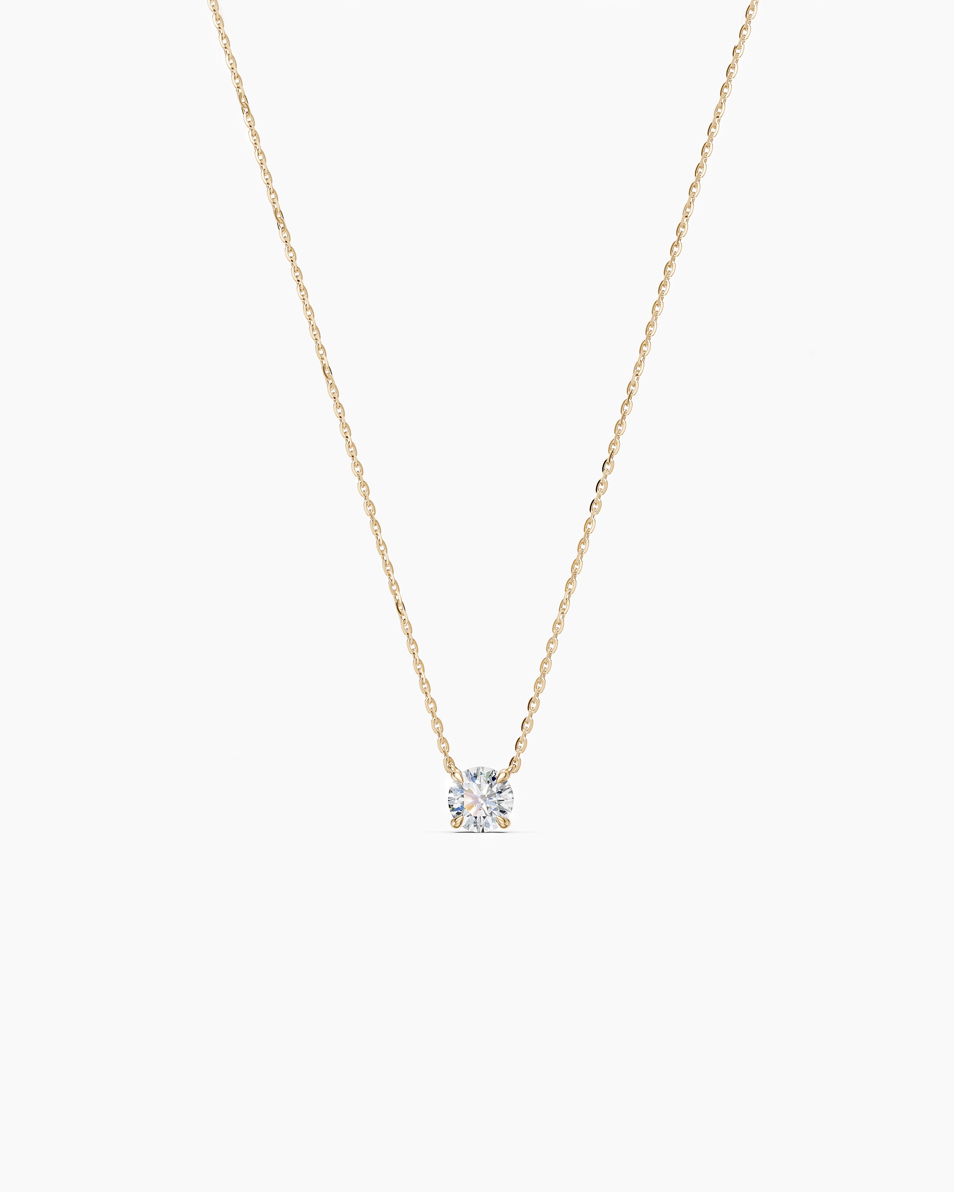 Yellow gold necklace with a round diamond pendant on a soft beige background