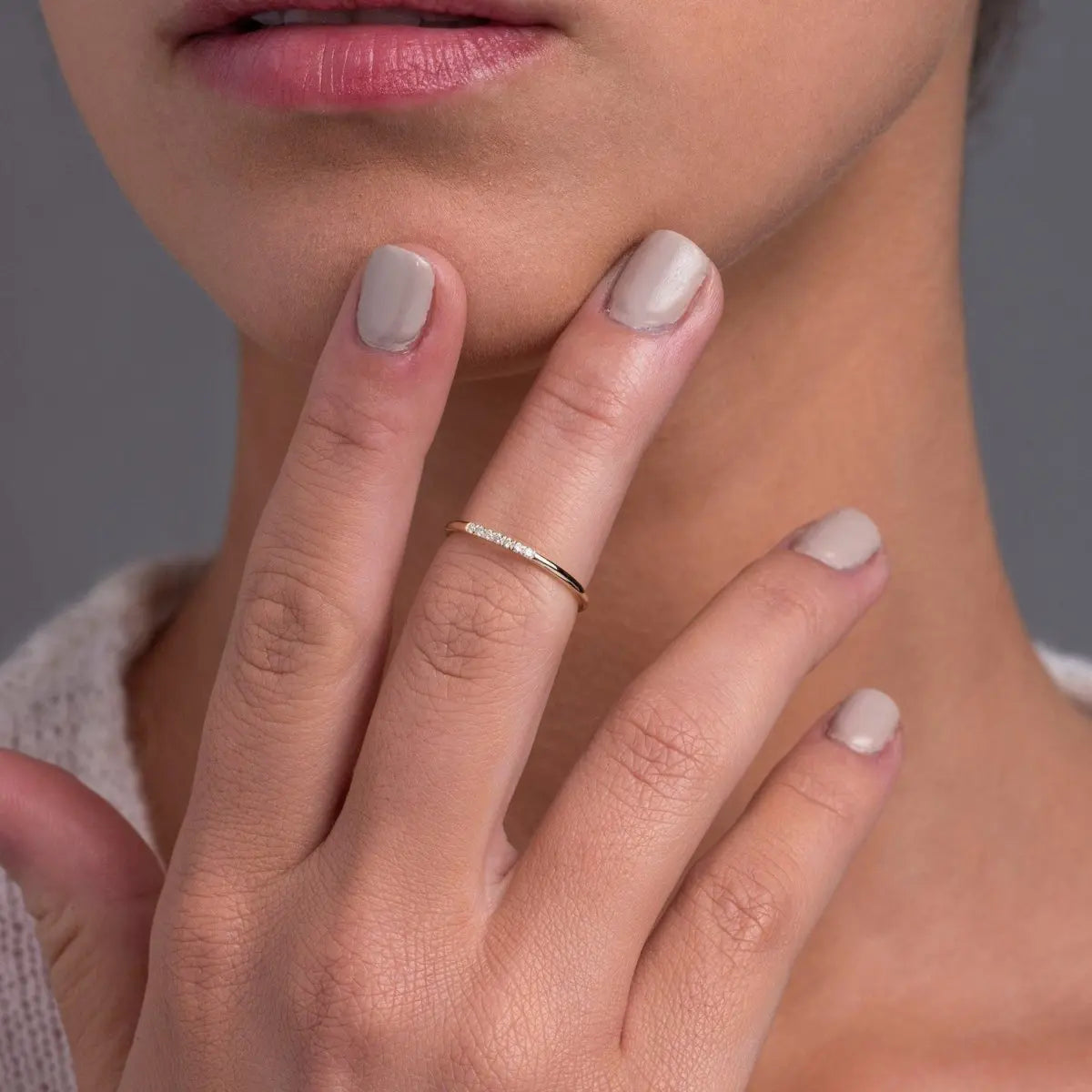 Model wearing 14k rose gold thin pave diamond stacking band ring, lifestyle close up of hand with delicate diamond ring near face