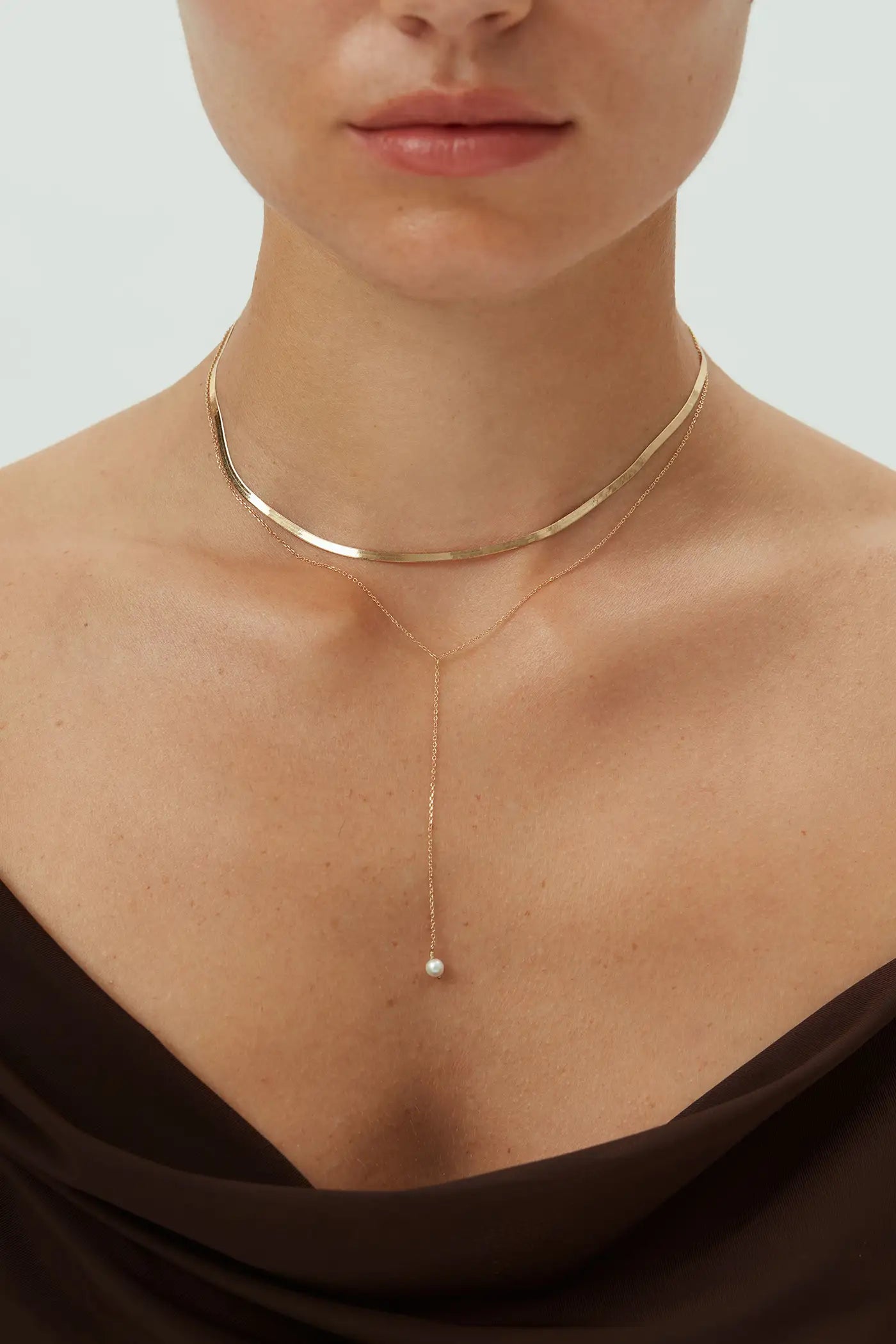 14k yellow gold lariat pearl necklace on model layered with gold choker showing freshwater pearl drop pendant on delicate chain