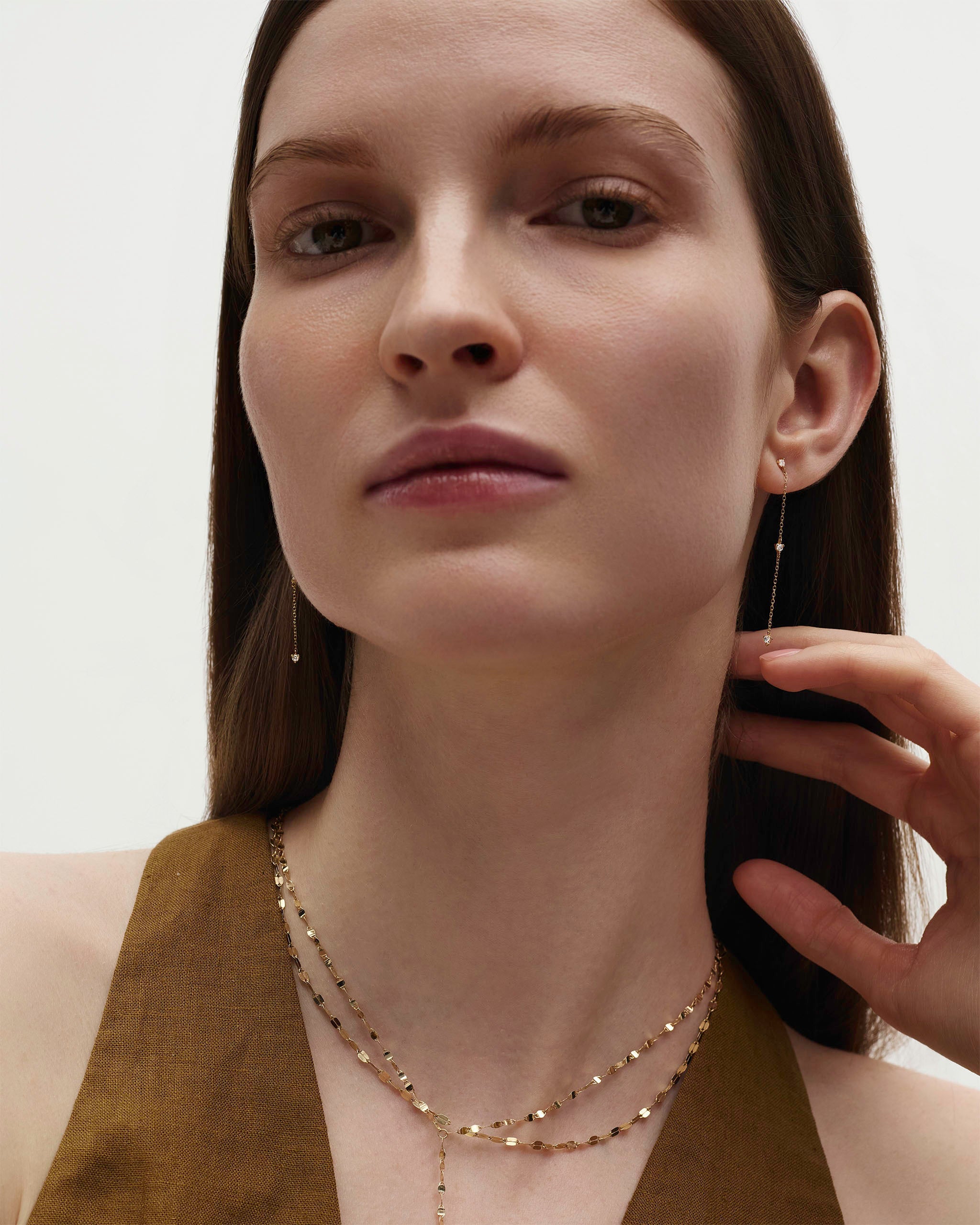 Delicate gold dangle earrings with three prong-set diamonds