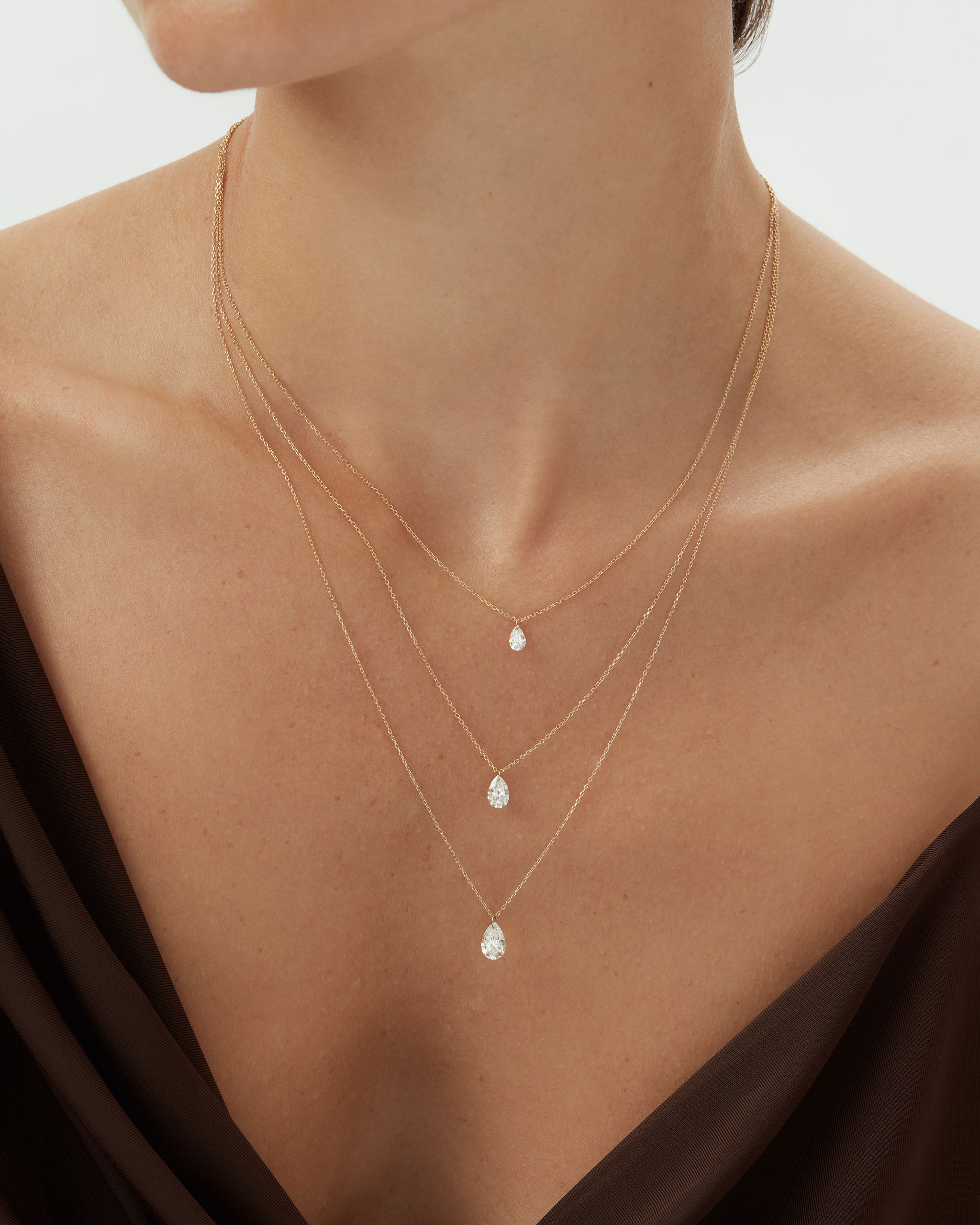 Layered pear shaped lab grown diamond necklaces in 14k solid gold, two delicate chains worn together with floating pear cut diamonds in graduated sizes
