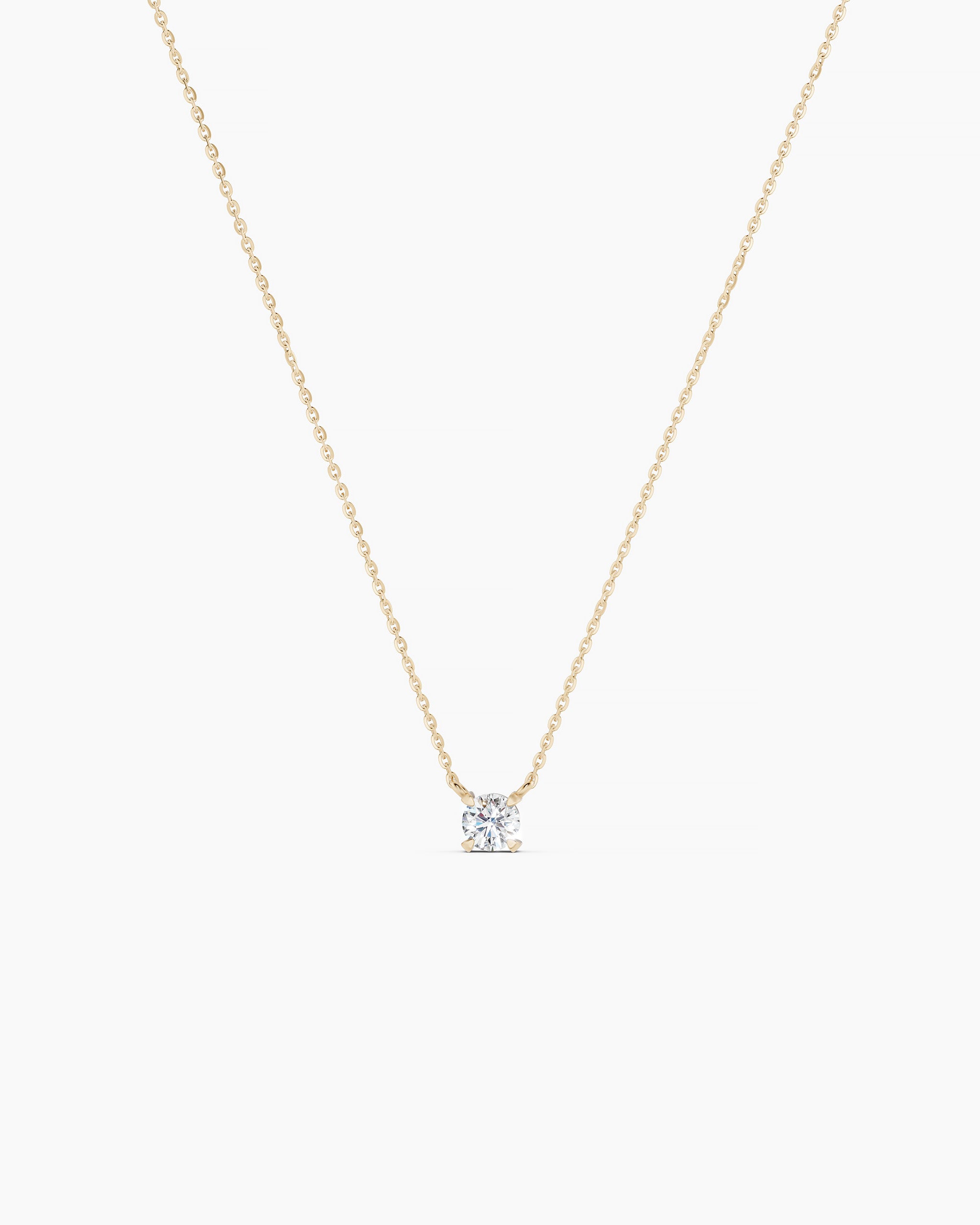 Gold necklace with a diamond pendant on a grey background