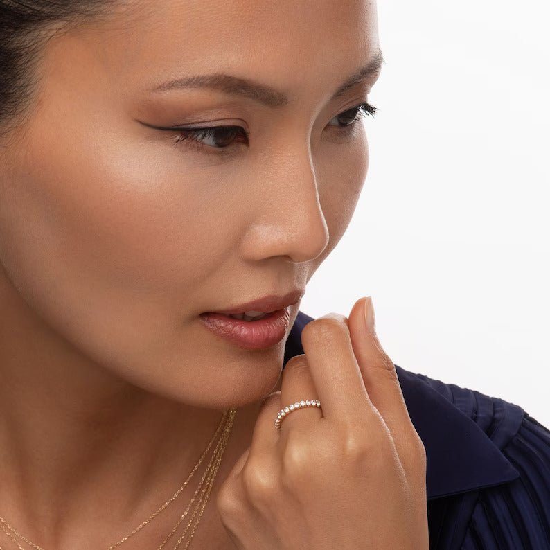 close-up of a model wearing the diamond eternity band, styled with layered necklaces for a sophisticated and modern jewelry look