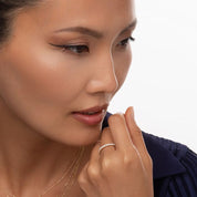 close-up of a model wearing the diamond eternity band, styled with layered necklaces for a sophisticated and modern jewelry look