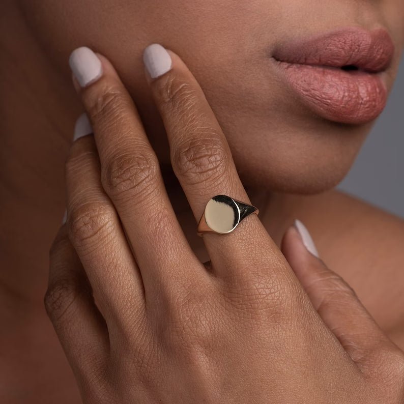 Model wearing the yellow gold oval signet ring on her index finger, styled with a minimalist gold chain necklace for a refined, modern look
