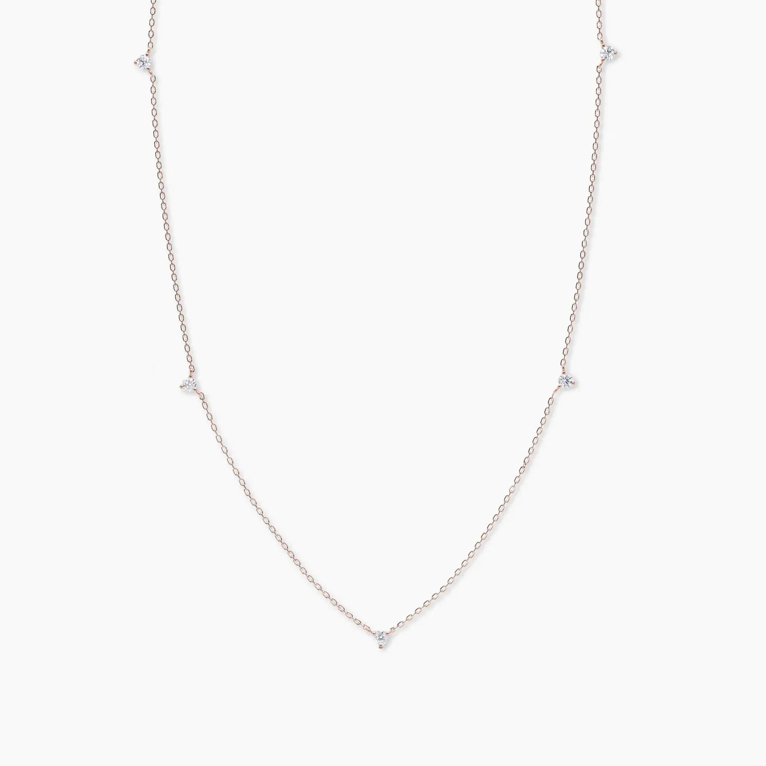 Rose gold necklace featuring five delicate white diamonds spaced evenly along a fine chain, displayed on a white background.
