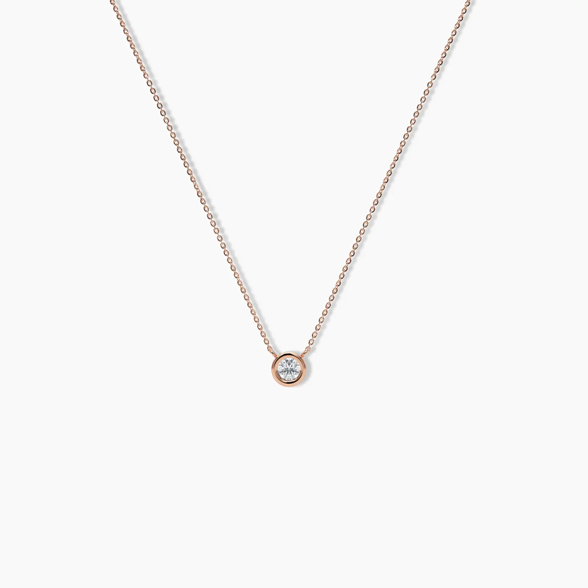 Delicate rose gold necklace featuring a round bezel-set diamond pendant on a fine chain, shown on a white background.

