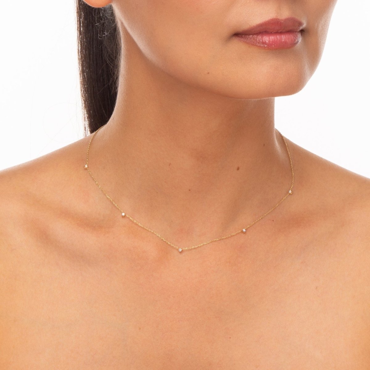 Model shot featuring a yellow gold solid chain with three delicate bezel-set diamonds.

