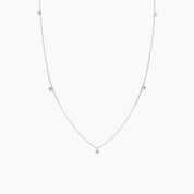 Delicate white gold necklace with small diamonds on a light gray background