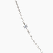 Close-up of a round white diamond set on a 14k white gold chain necklace, showcasing delicate craftsmanship

