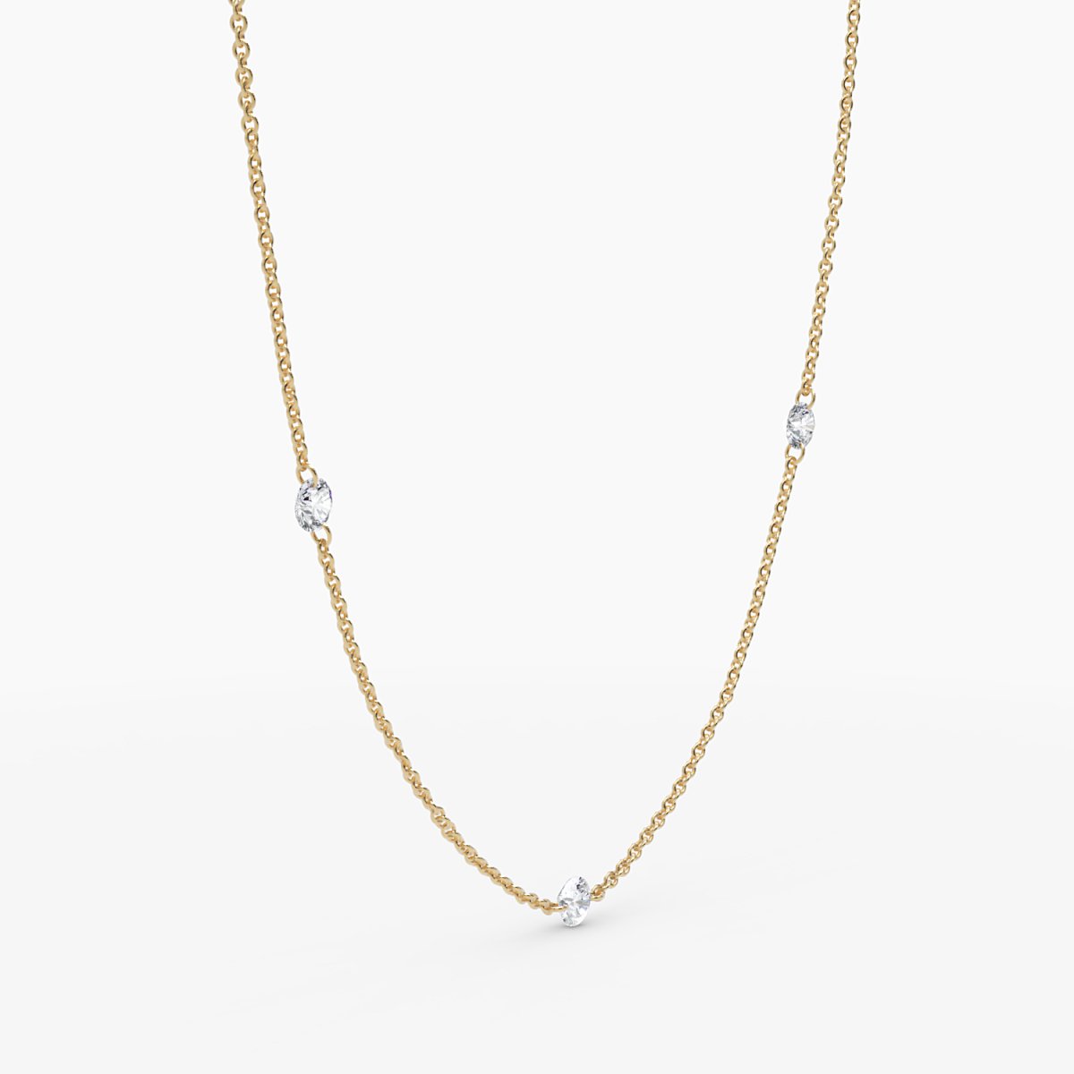 Angled view of yellow gold necklace with bezel-set diamonds evenly spaced, styled in a soft curve.

