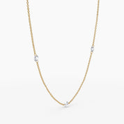 Angled view of yellow gold necklace with bezel-set diamonds evenly spaced, styled in a soft curve.

