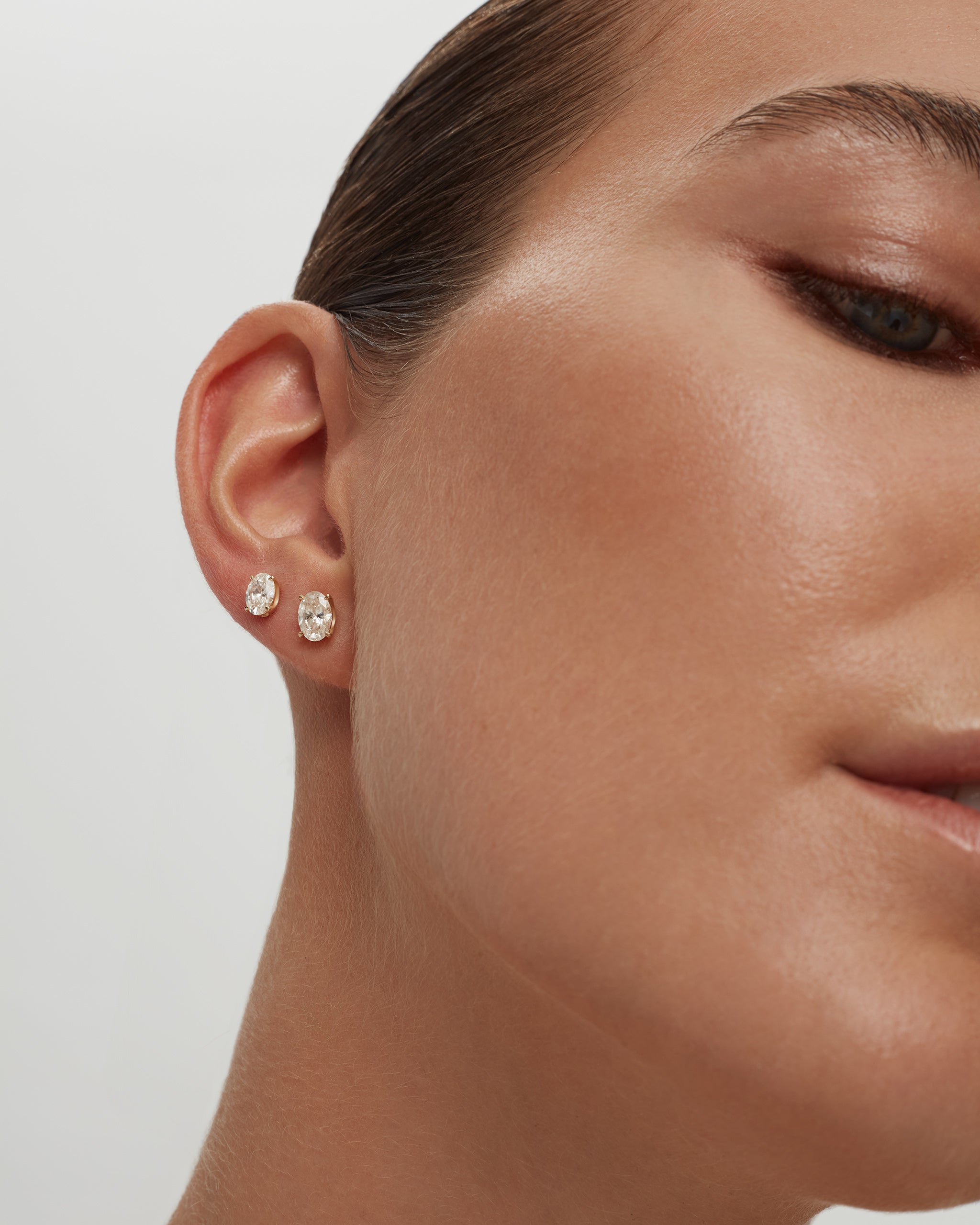 Model wearing oval lab diamond stud earrings in 14k yellow gold on the lobe and second piercing, ENEA Studio