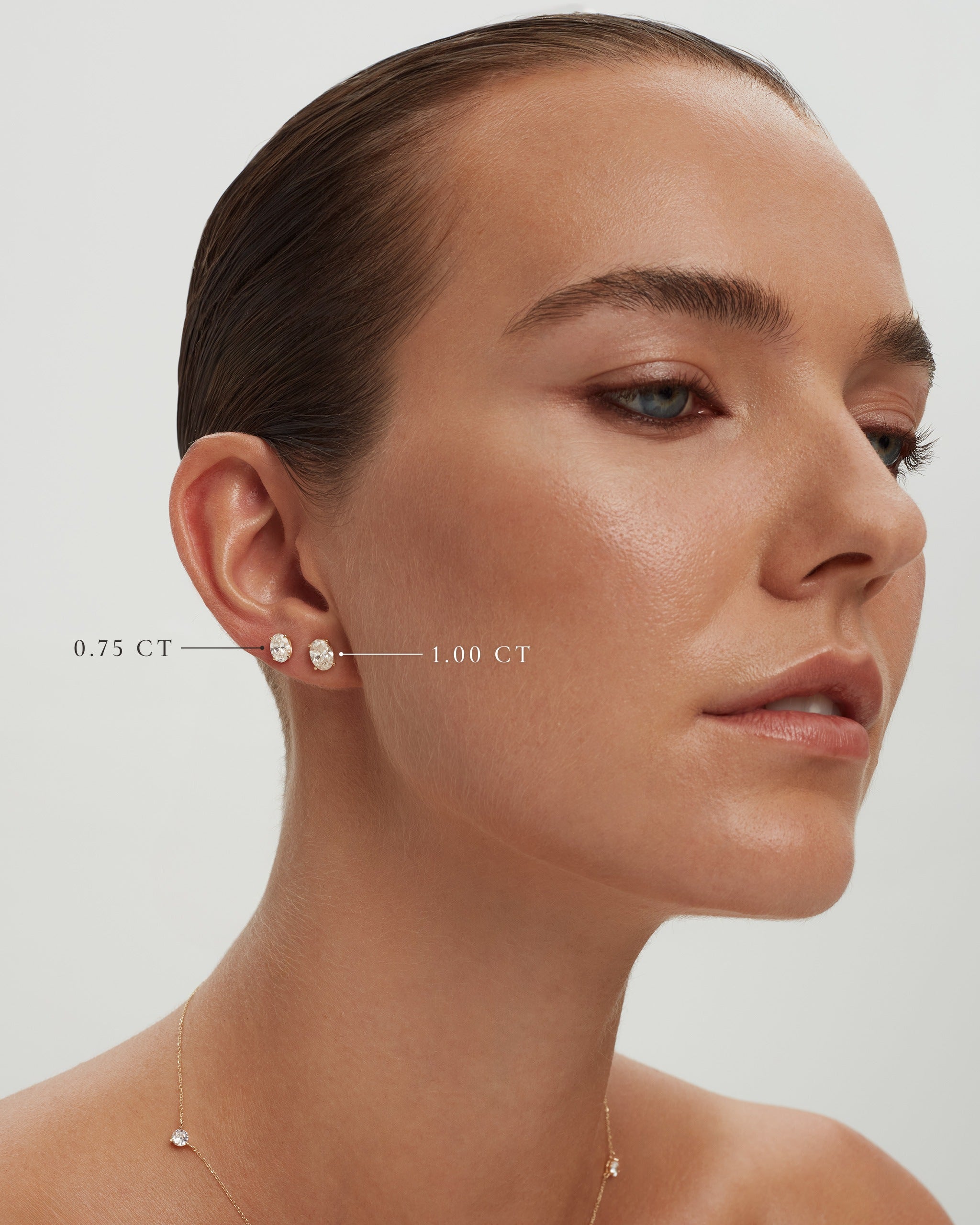 Model wearing oval lab diamond studs in 14k yellow gold, 0.75 ct and 1.00 ct each, labelled, ENEA Studio