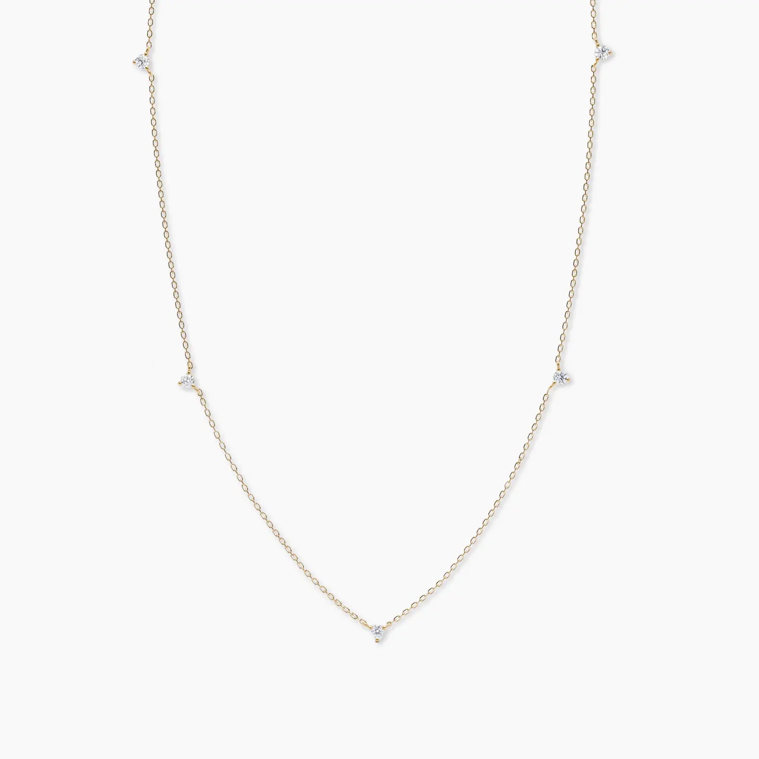 Yellow gold necklace featuring five evenly spaced round diamonds along a fine chain, displayed against a white background.
