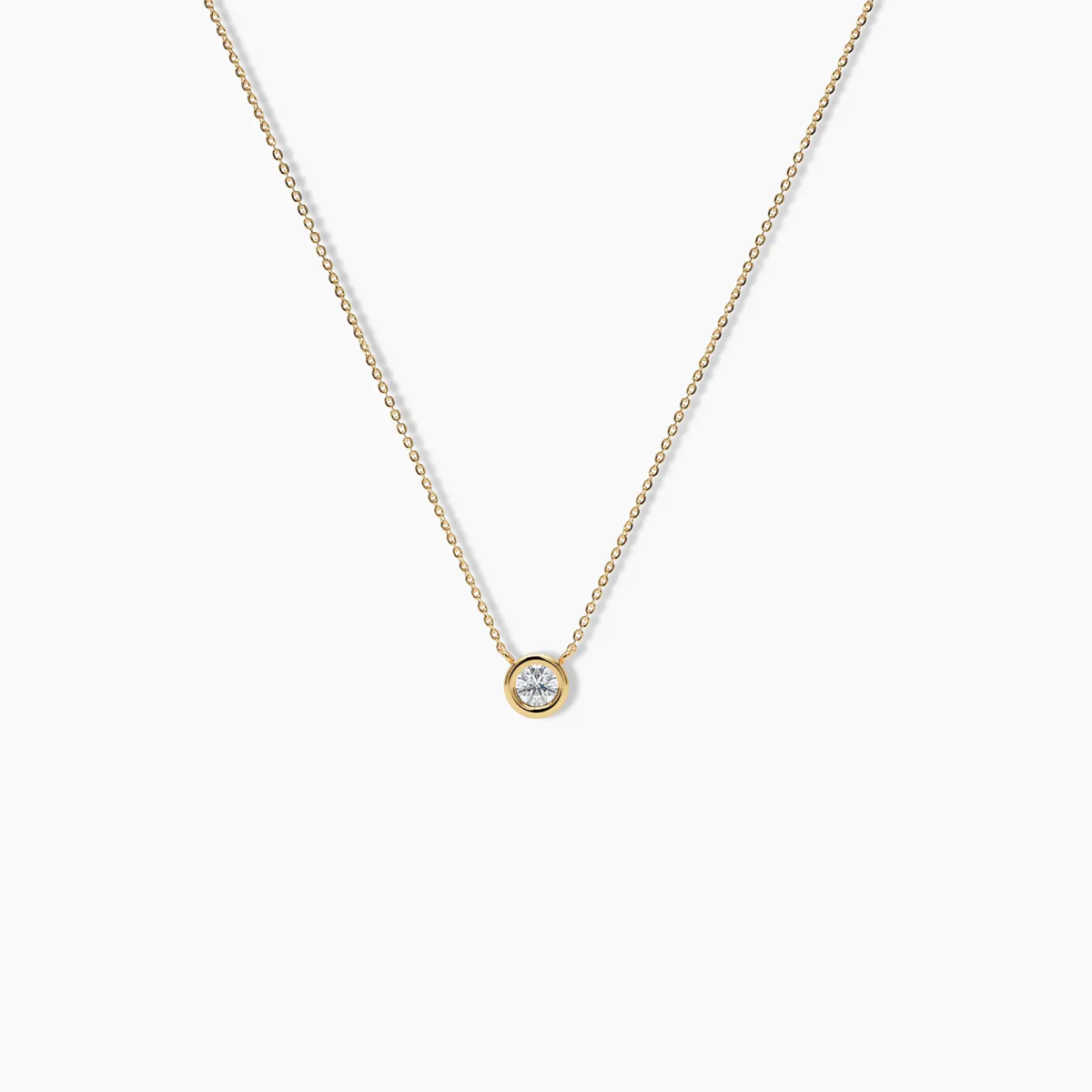 14k yellow gold necklace featuring a round bezel-set diamond pendant on a delicate chain, displayed against a white background.
