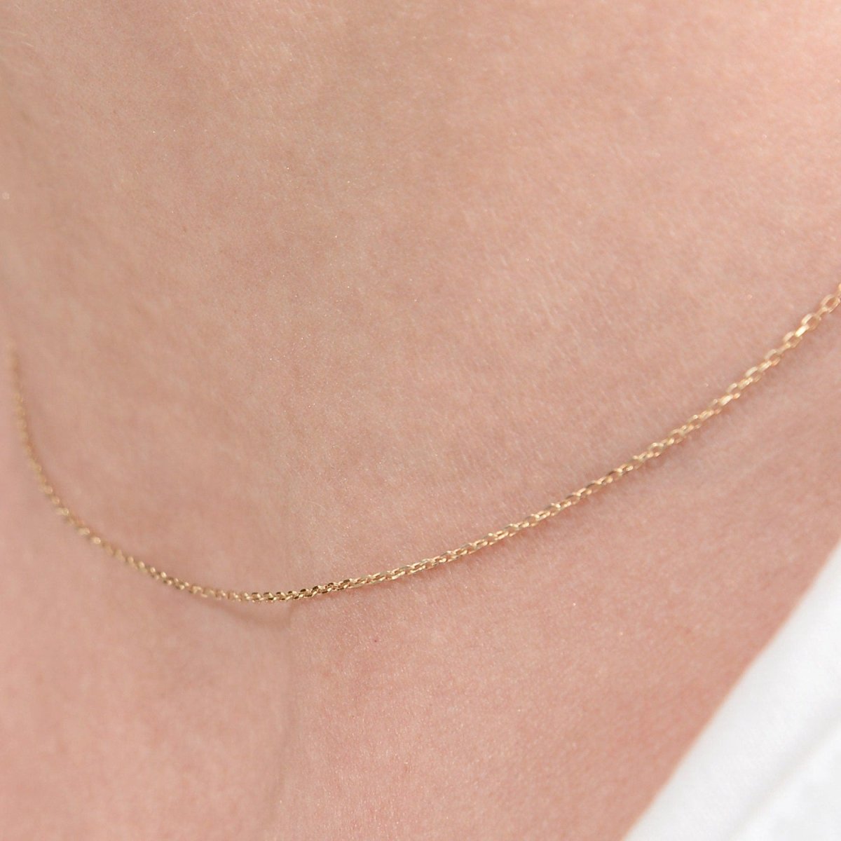 Tight crop of the chain resting on the collarbone, showing its fine, lightweight texture.

