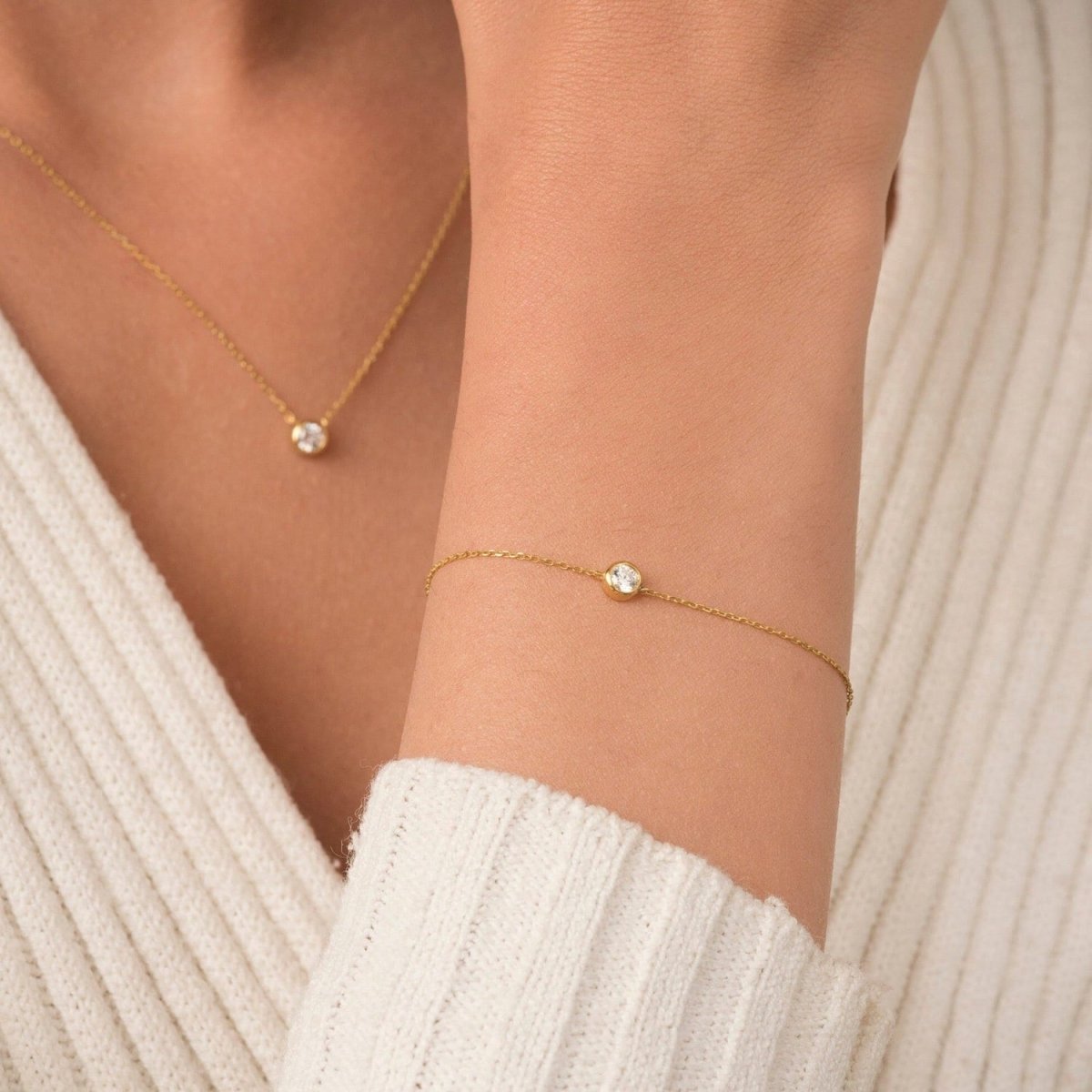 Model wearing a matching diamond necklace and bracelet set in yellow gold, styled with a cream sweater for a soft, elegant look.
