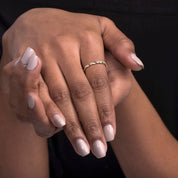 A woman’s hand styled with a 14k yellow gold twisted diamond eternity band, capturing its delicate twisted structure and shimmering row of diamonds.