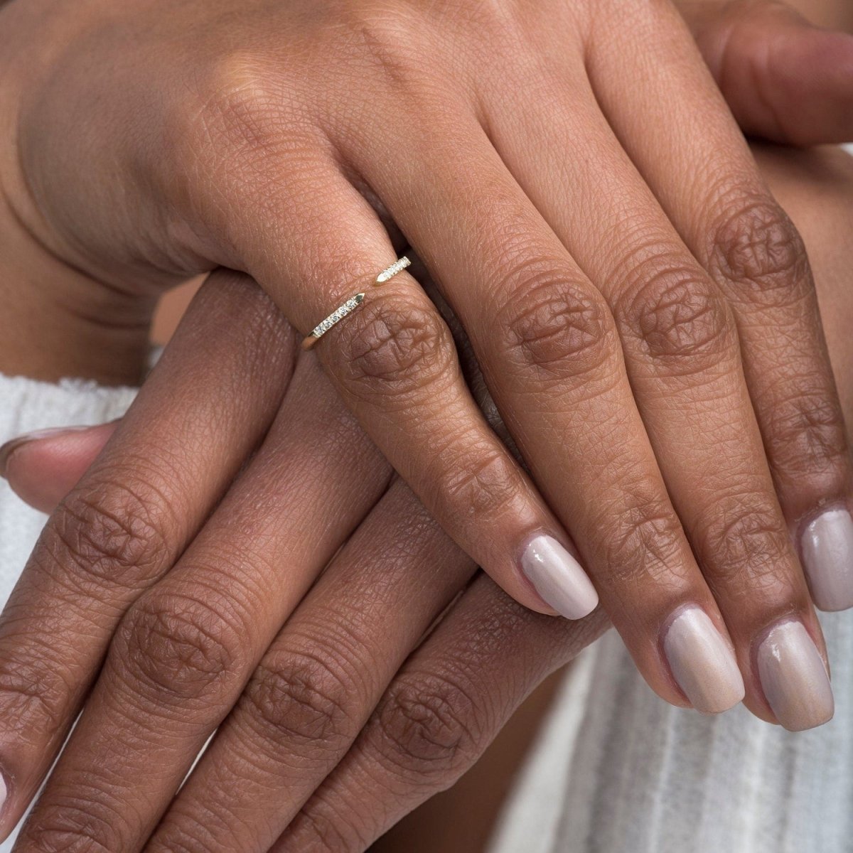 close-up of a model’s hands stacked with multiple rings, featuring the open cuff diamond ring in white gold as a centerpiece
