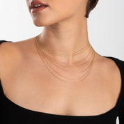 Model wearing four chain lengths stacked together, showcasing layering versatility of the gold chains.

