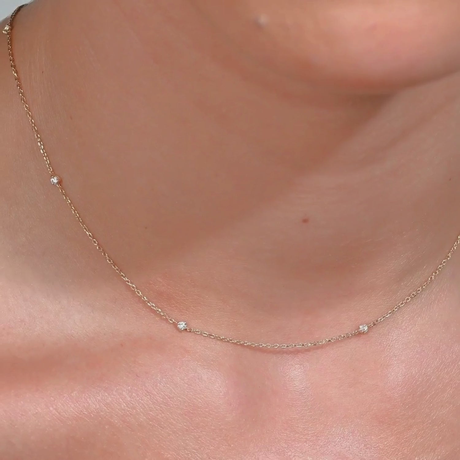 Video showing a 14k gold necklace with tiny diamonds shimmering on the neckline, highlighting how it moves naturally with the body
