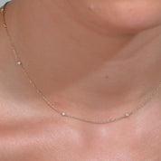 Video showing a 14k gold necklace with tiny diamonds shimmering on the neckline, highlighting how it moves naturally with the body
