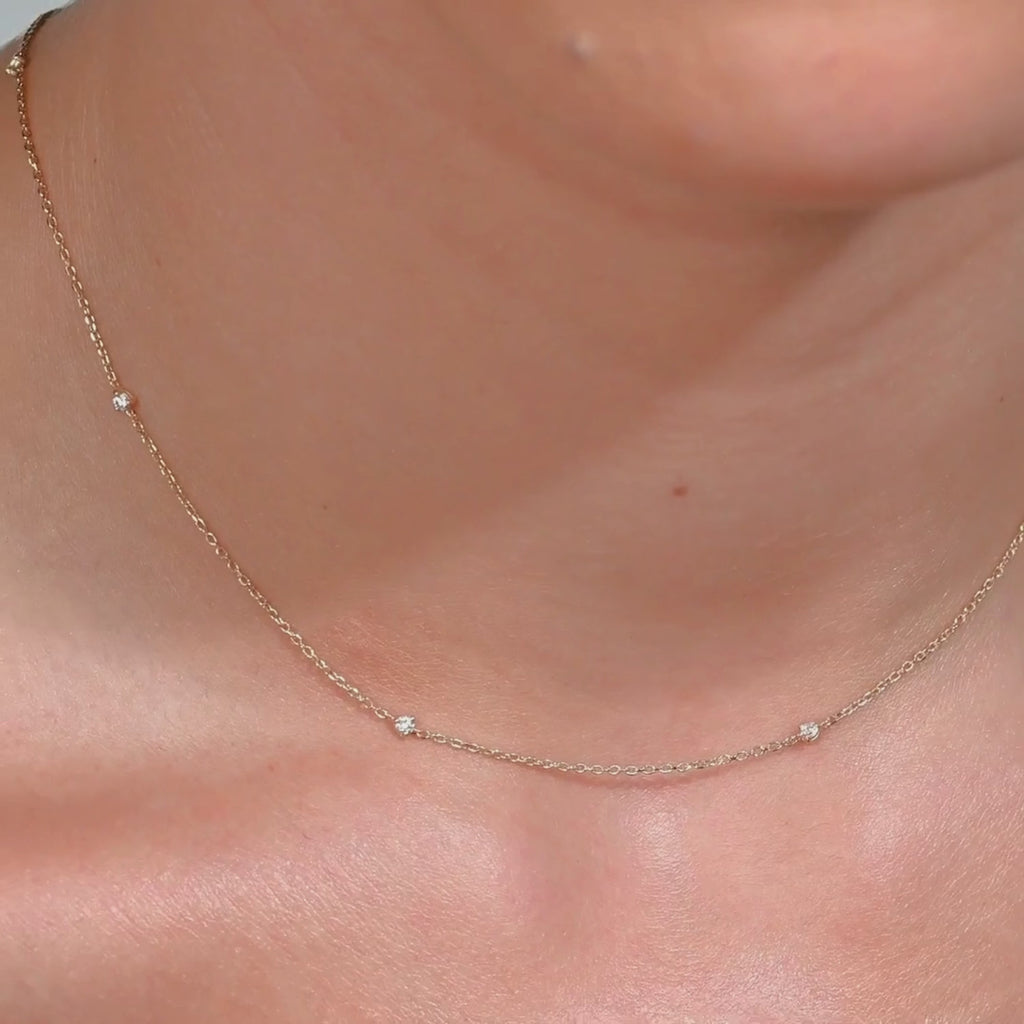 Video showing a 14k gold necklace with tiny diamonds shimmering on the neckline, highlighting how it moves naturally with the body
