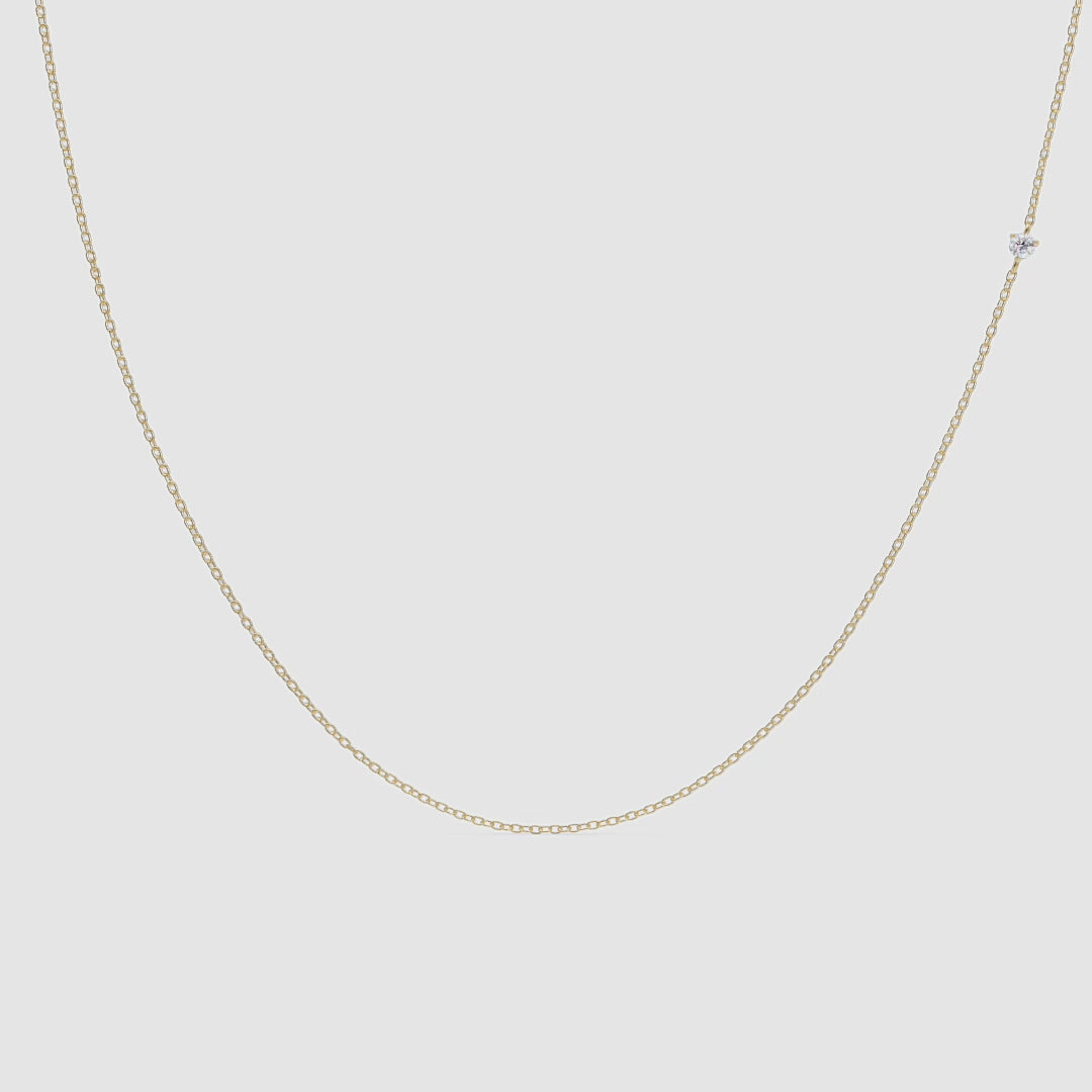 Close-up video of a delicate gold chain necklace with a single small diamond station. The necklace hangs gently against a white background, with soft lighting highlighting the sparkle of the diamond as the chain subtly sways.
