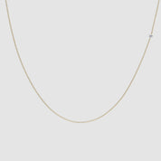 Close-up video of a delicate gold chain necklace with a single small diamond station. The necklace hangs gently against a white background, with soft lighting highlighting the sparkle of the diamond as the chain subtly sways.
