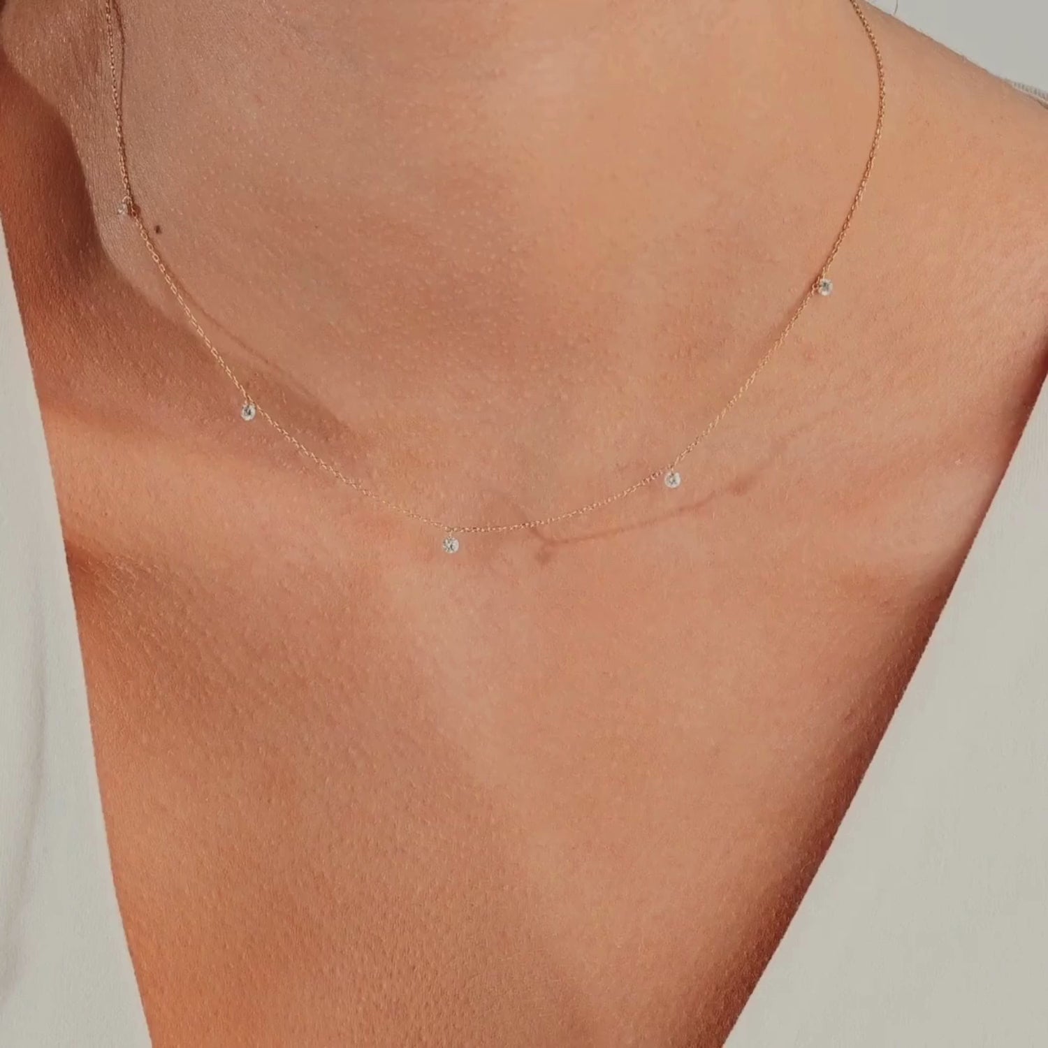 14k gold necklace with spaced round diamonds, shown worn close to the neck on a model, highlighting its barely-there shimmer and delicate floating design.
