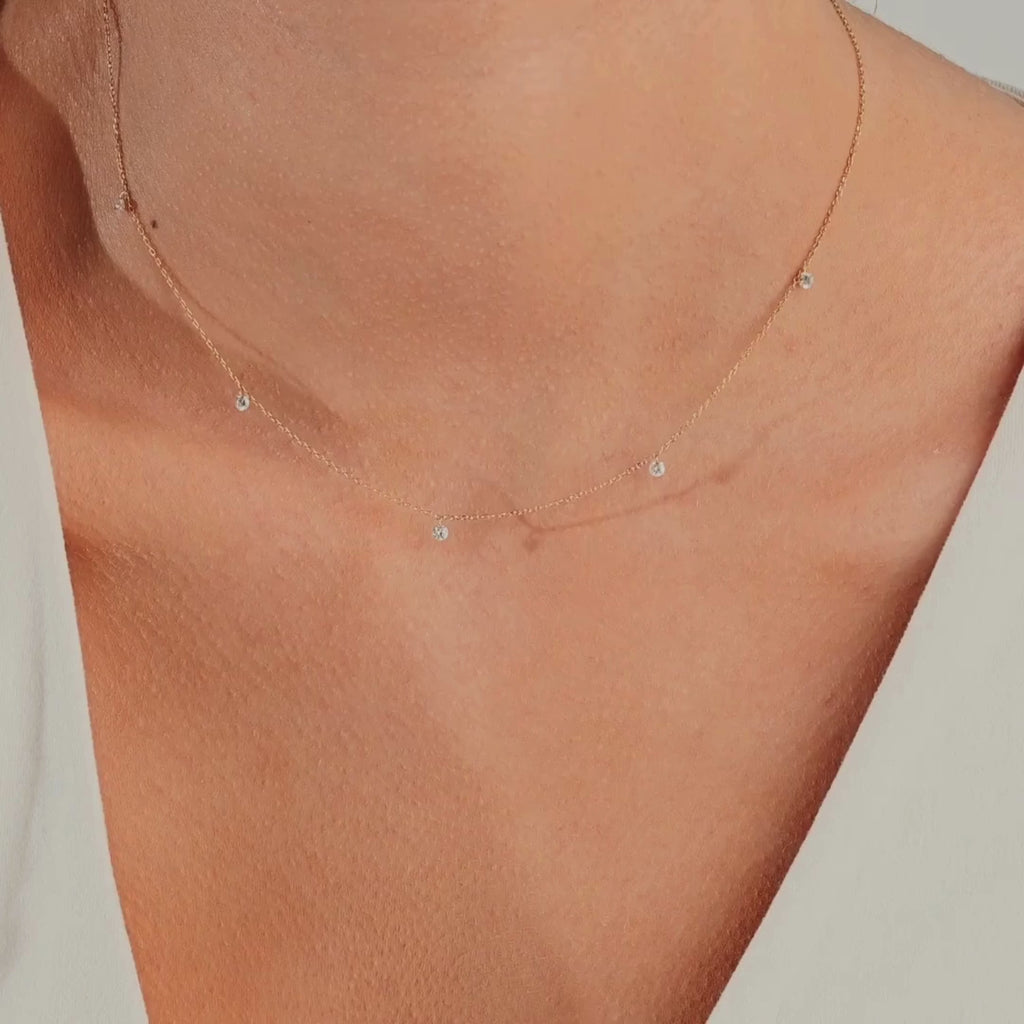 14k gold necklace with spaced round diamonds, shown worn close to the neck on a model, highlighting its barely-there shimmer and delicate floating design.
