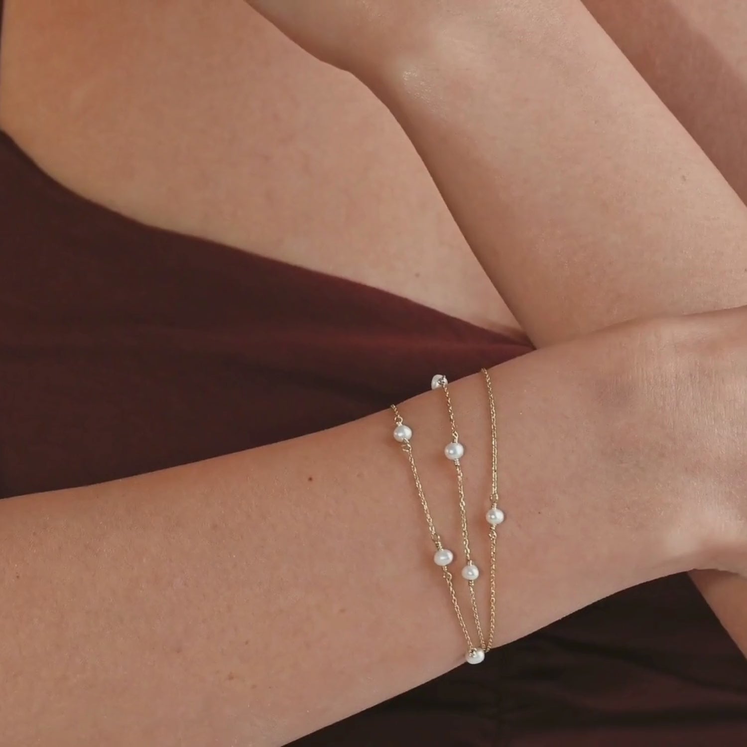 Close-up of 14k yellow gold bracelet with luminous white pearls styled on bare skin.