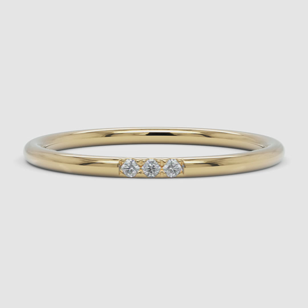 A 360-degree video of a 14k yellow gold slim diamond band, smoothly rotating to reveal its fine, polished band and three round diamonds set in a delicate arrangement.